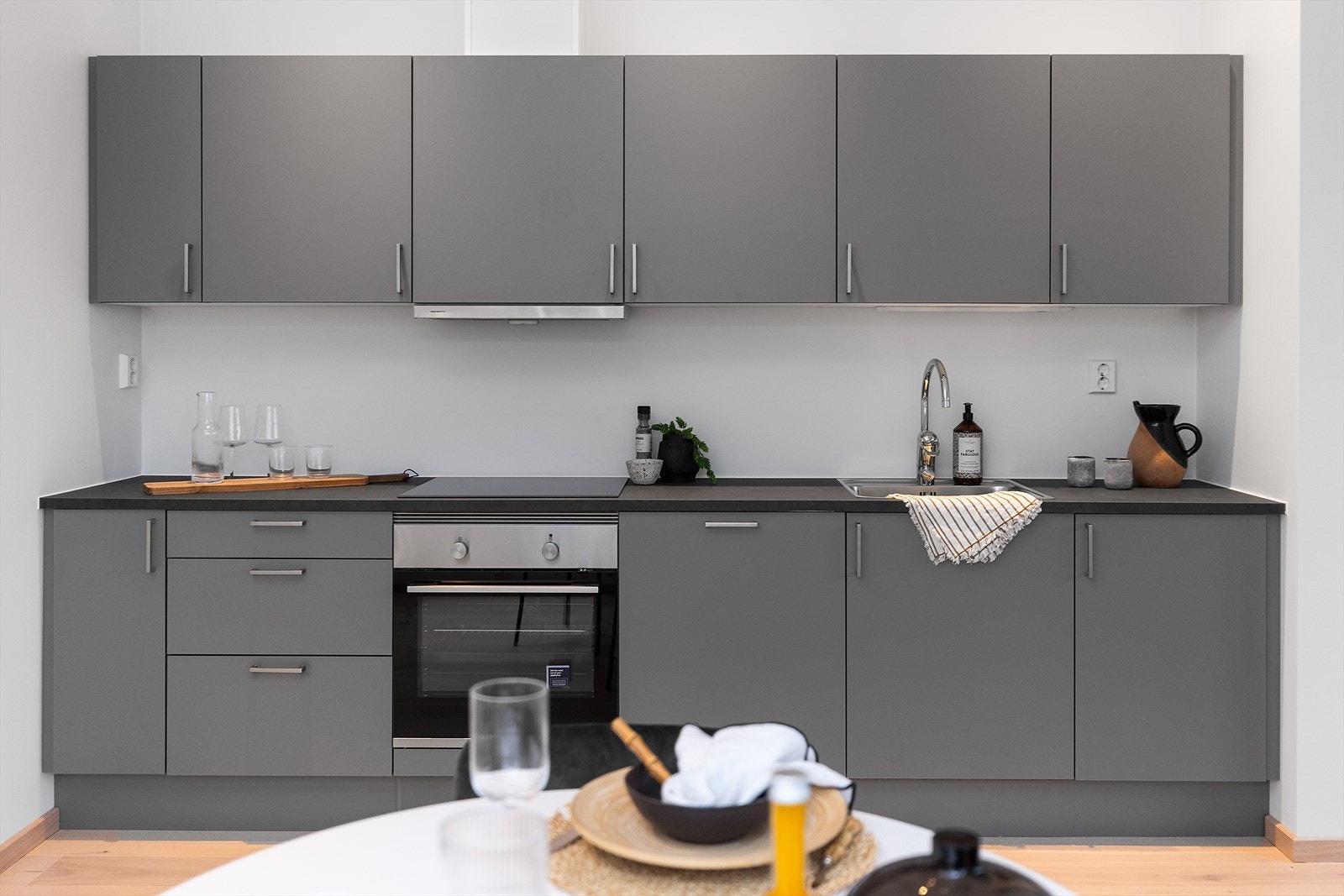 Lekkert kjøkken fra HTH med glatte fronter og laminat benkeplate. Det leveres hvitevarer som stekeovn, induksjonstopp, oppvaskmaskin og ventilator. Galleribilde