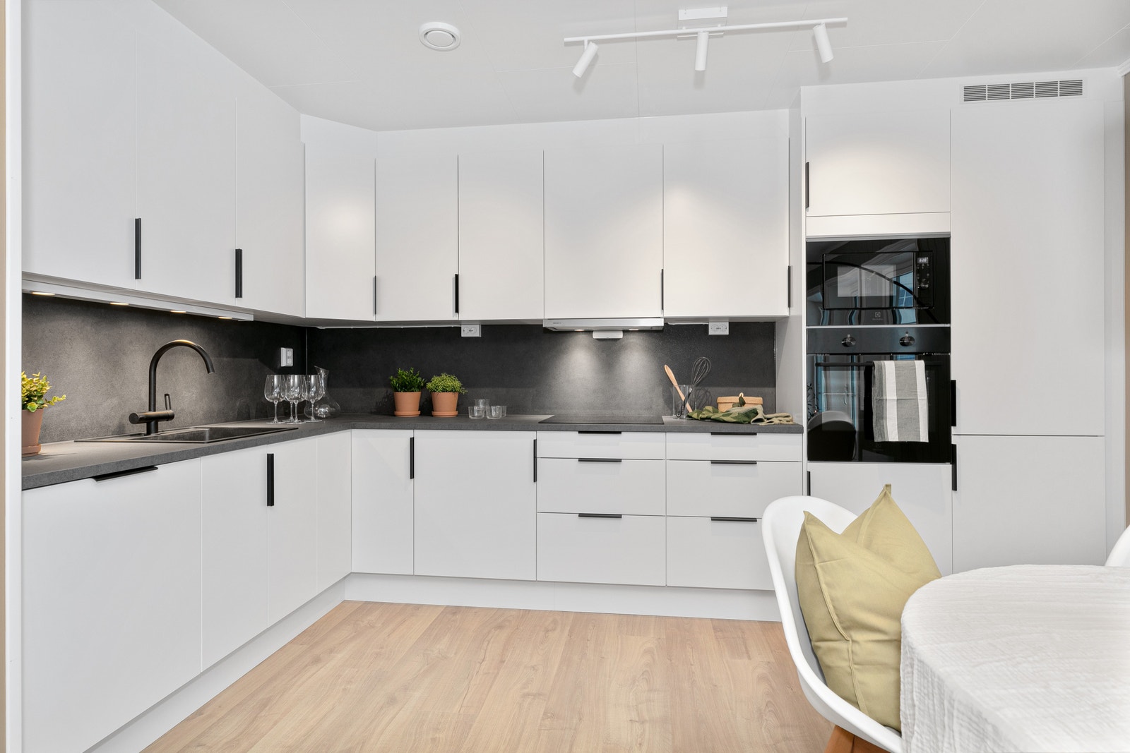 Moderne kvalitetskjøkken fra Sigdal av typen Uno, integrerte hvitevarer med helsort front. Sammen med naturlig lys fra kjøkkenvinduet, er kjøkkenet godt belyst med dimbar spotskinne i tak, samt spoter under overskapene. Galleribilde