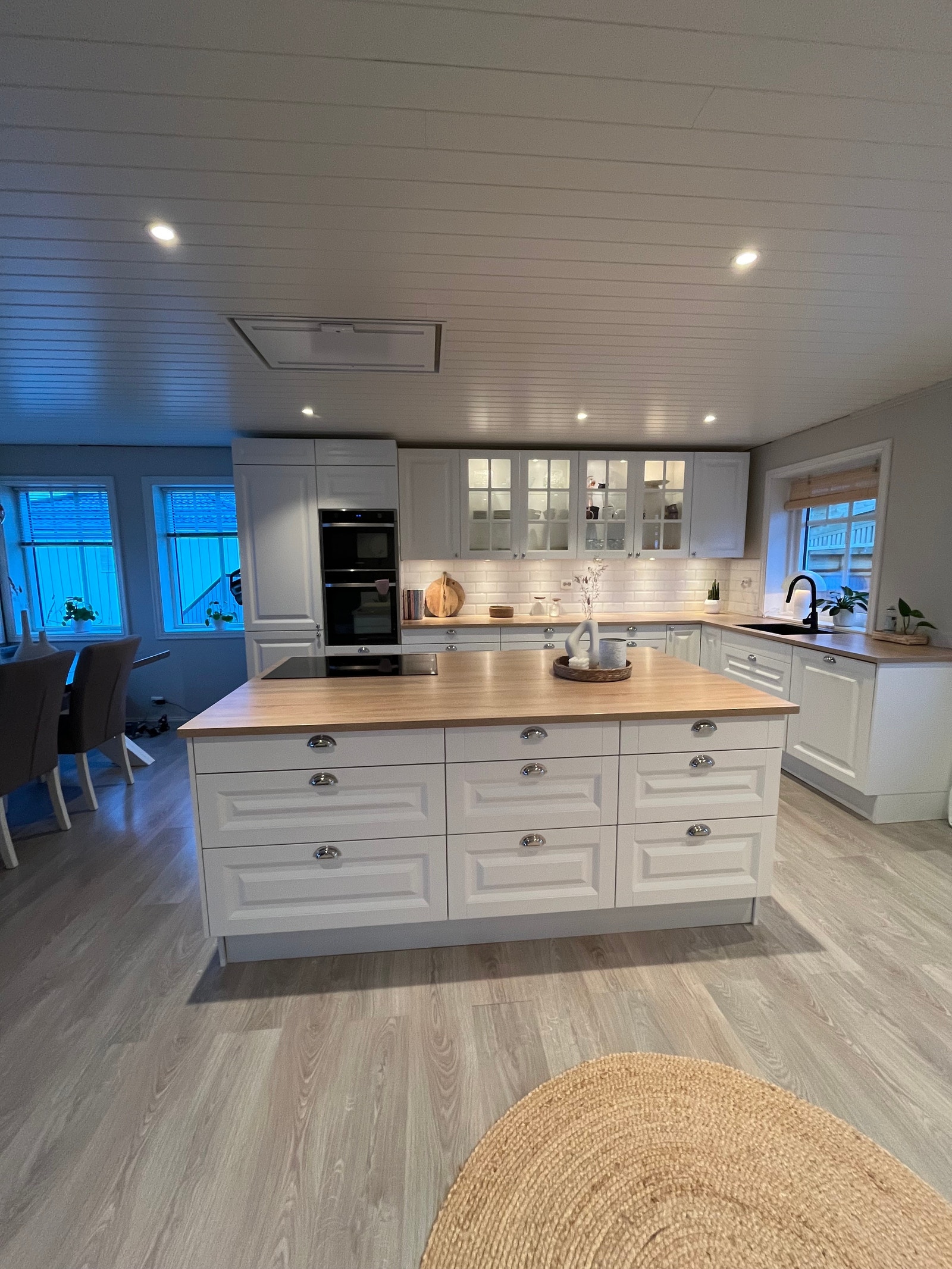 Kjøkkeninnredning lyst å stilrent med en lys eikefarget benkeplate og stilrene fliser over benkeplate. Galleribilde