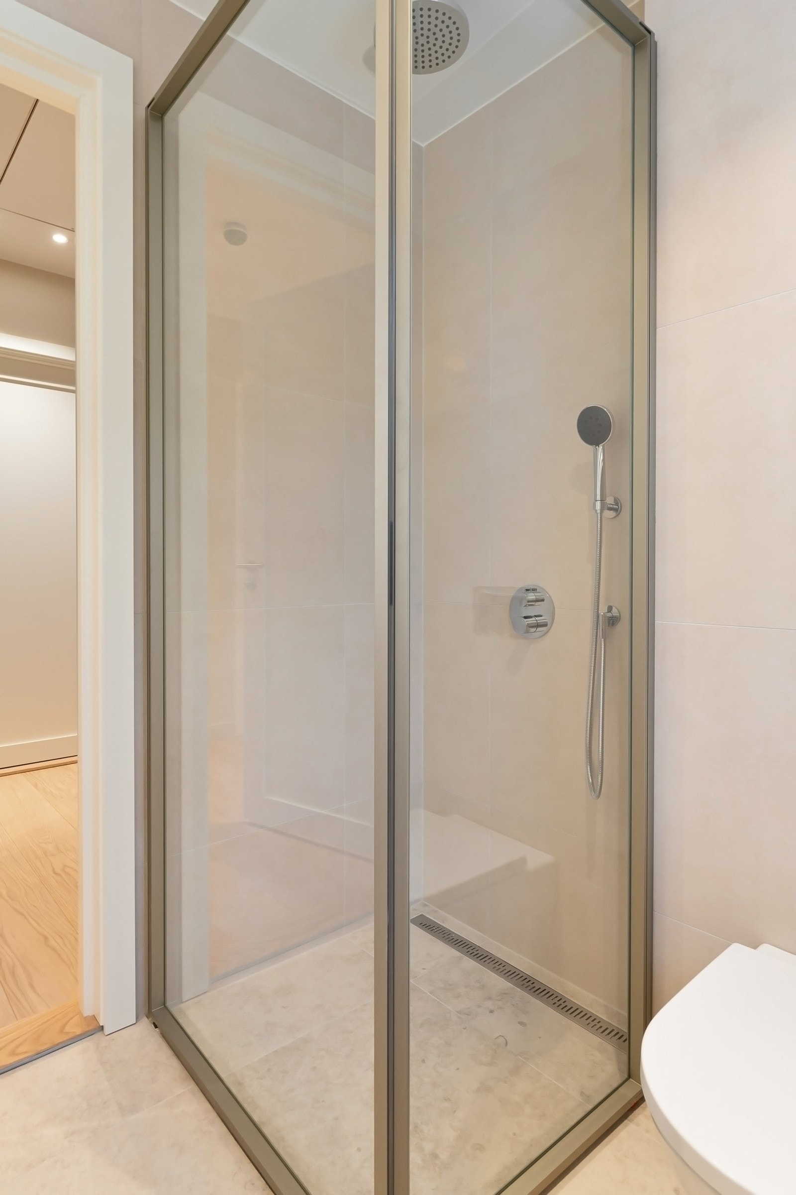 Badet er innredet med vegghengt toalett, dusjhjørne med glassdører og en stilfull baderomsinnredning fra Dansani. Galleribilde