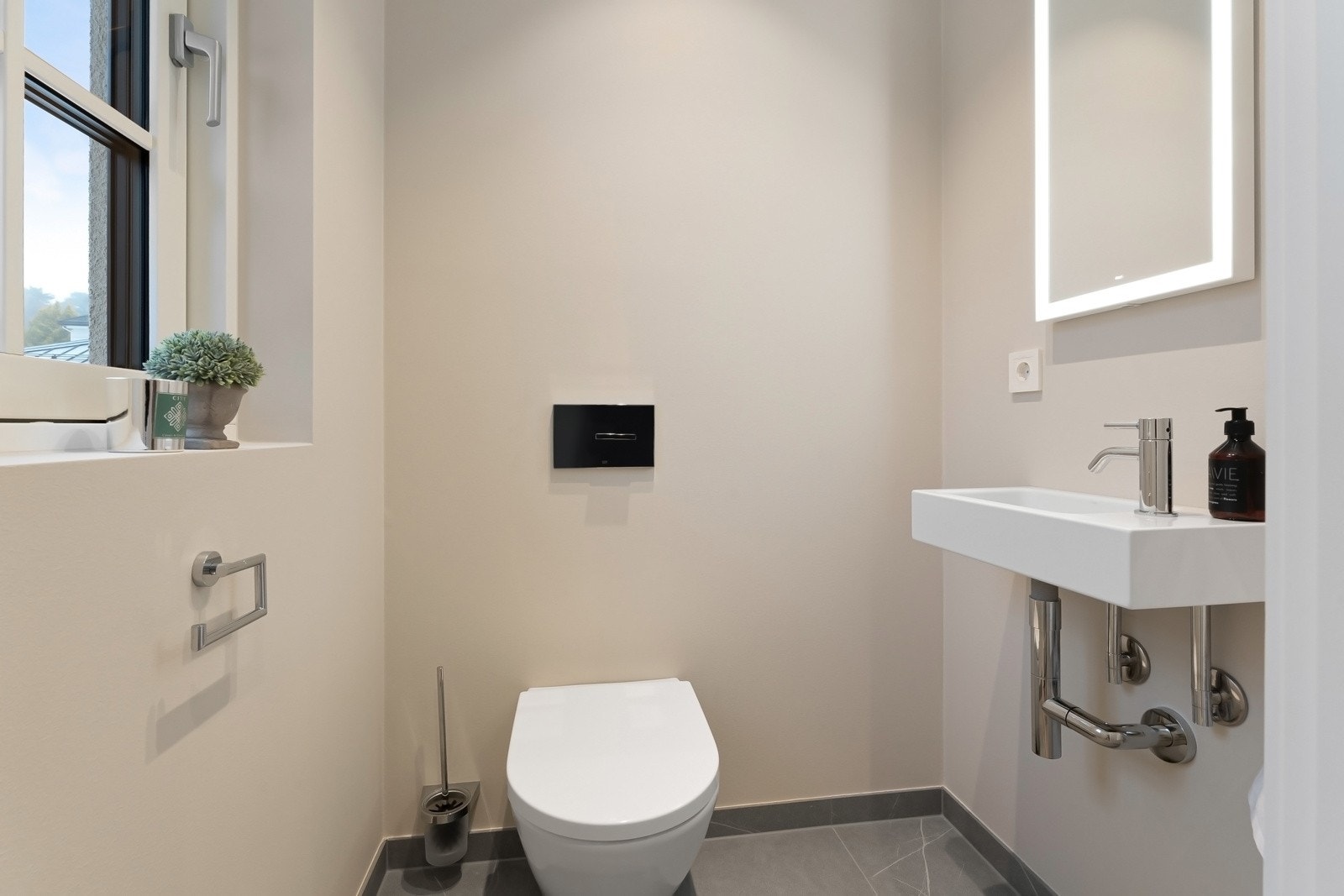Toalettrommet har de samme smakfulle gulvflisene som badene, mens vegger er malt i fargen Kalk. Videre er det elektriske varmekabler, downlights, vegghengt toalett og armatur fra Dornbracht, samt servant og designspeil fra Dansani. Galleribilde