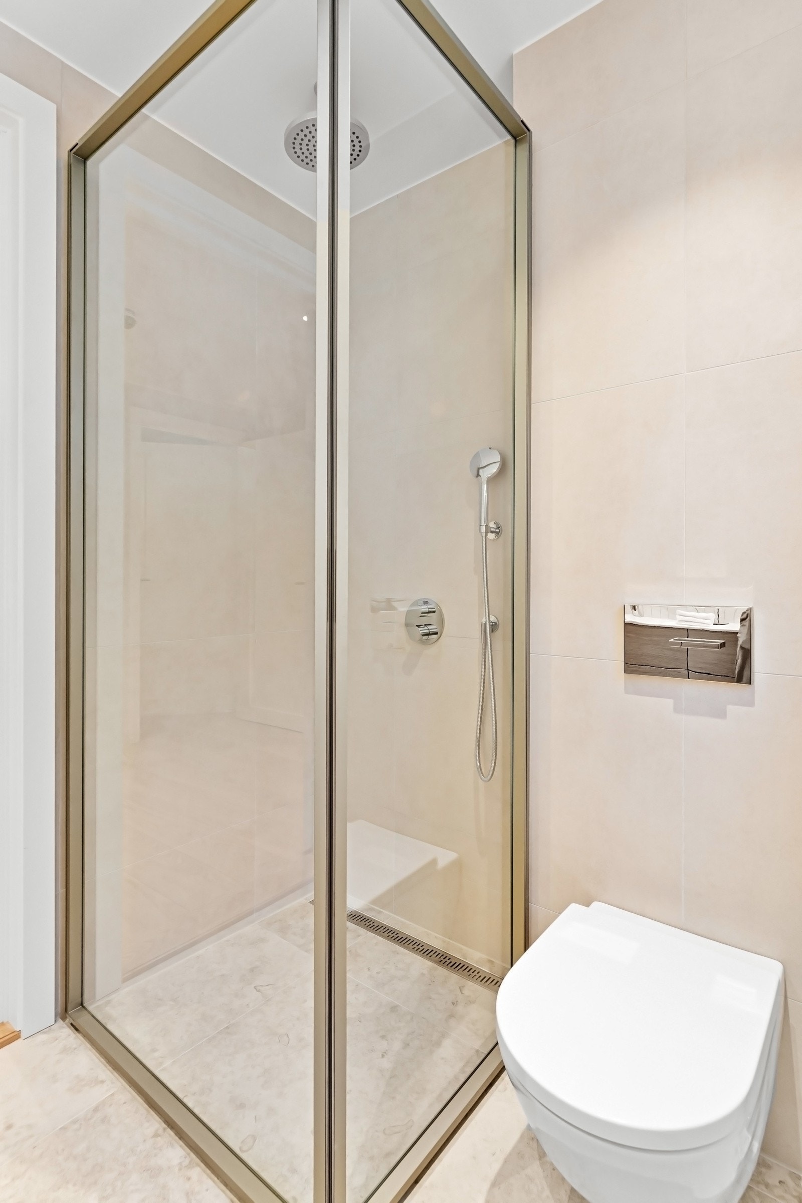 Badet er innredet med vegghengt toalett, dusjhjørne med glassdører og en stilfull baderomsinnredning fra Dansani. Galleribilde