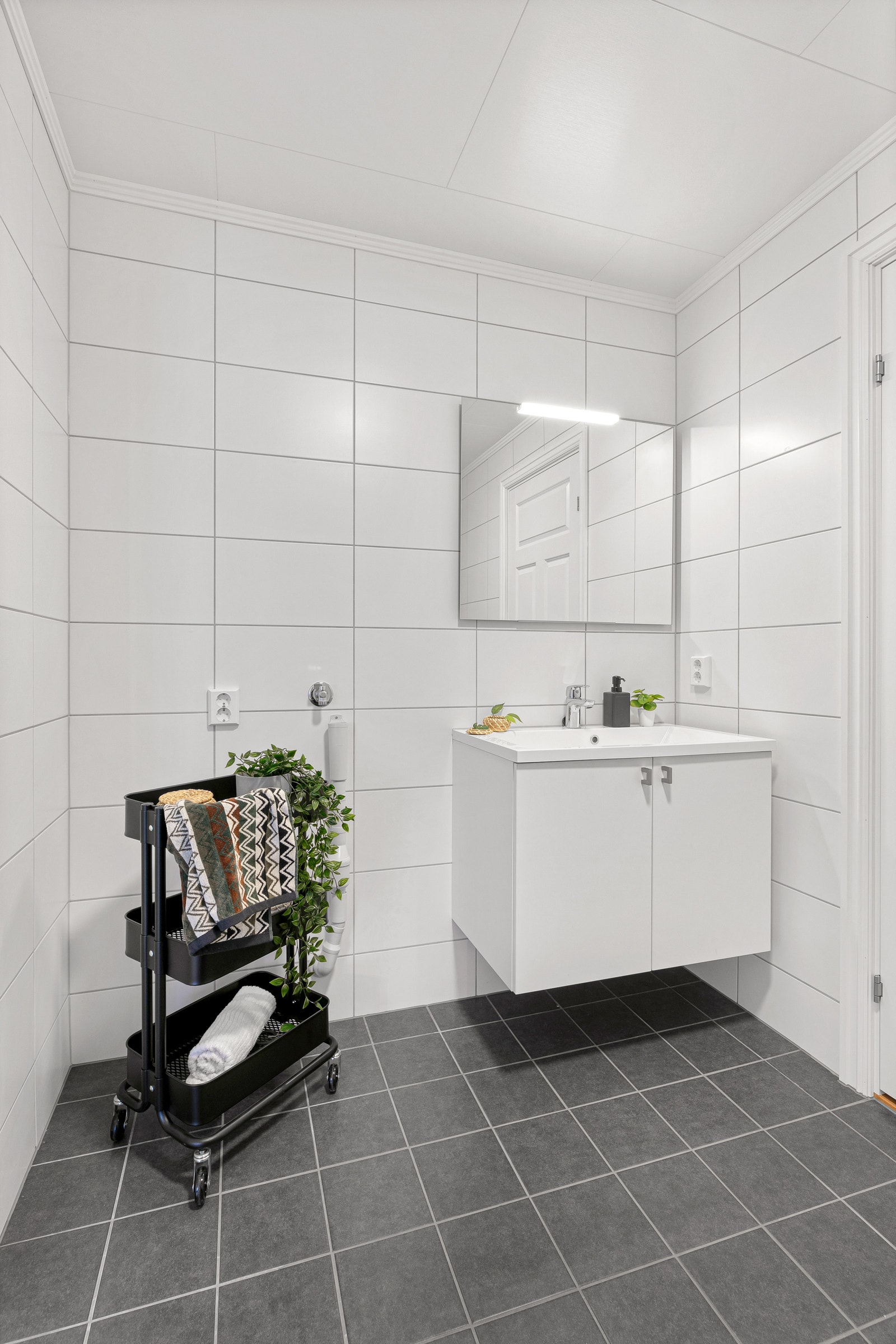 Bad med mørke fliser på gulv og lys innredning Galleribilde