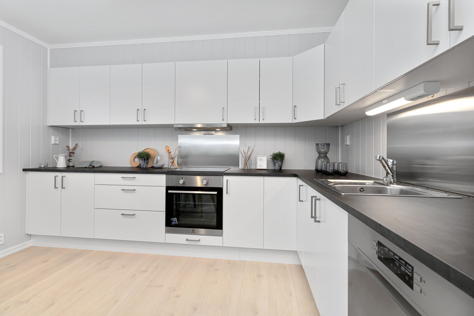 Kjøkken med lyse fronter og mørk benkeplate. Foto er fra annen leilighet med lik planløsning. Galleribilde