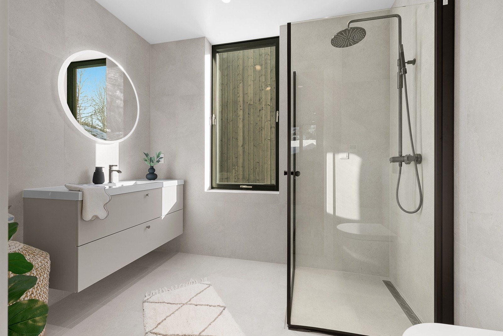 Delikat flislagt bad med dushjørne, servant med innredning og vegghengt toalett. Opplegg for vaskemaskin. Galleribilde