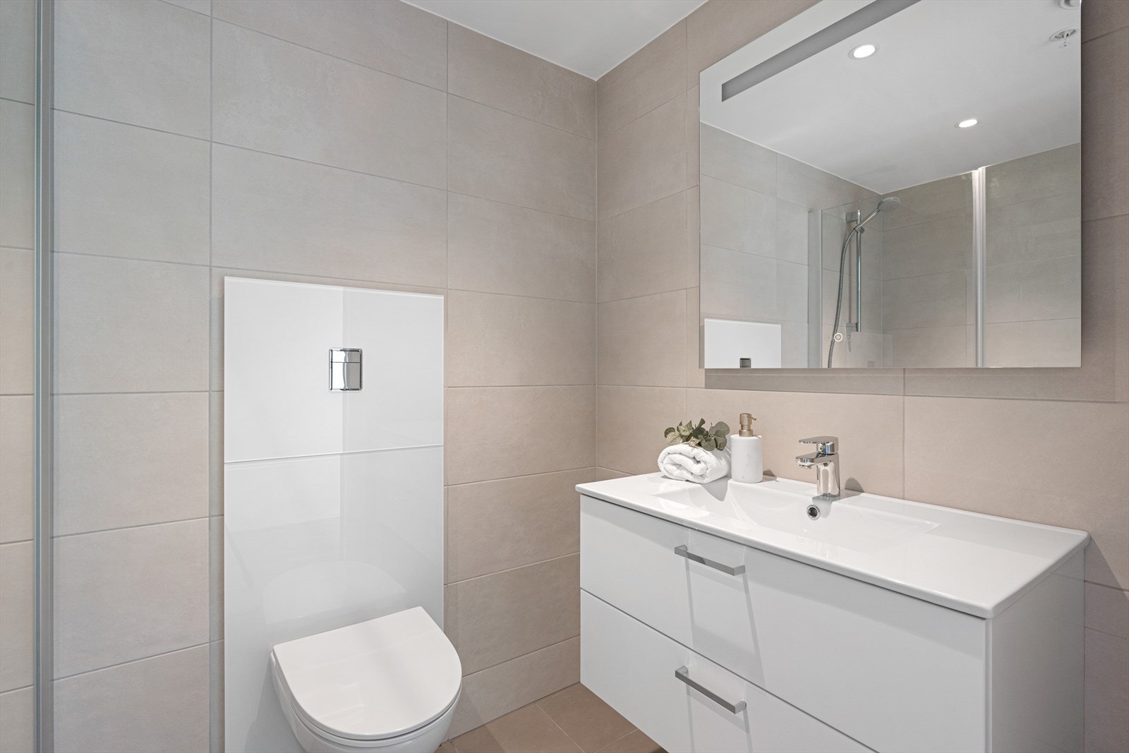 Lekkert bad med baderomsinnredning i hvitt porselen og skuffer med dempet lukking. Speil med integrert lys. Galleribilde