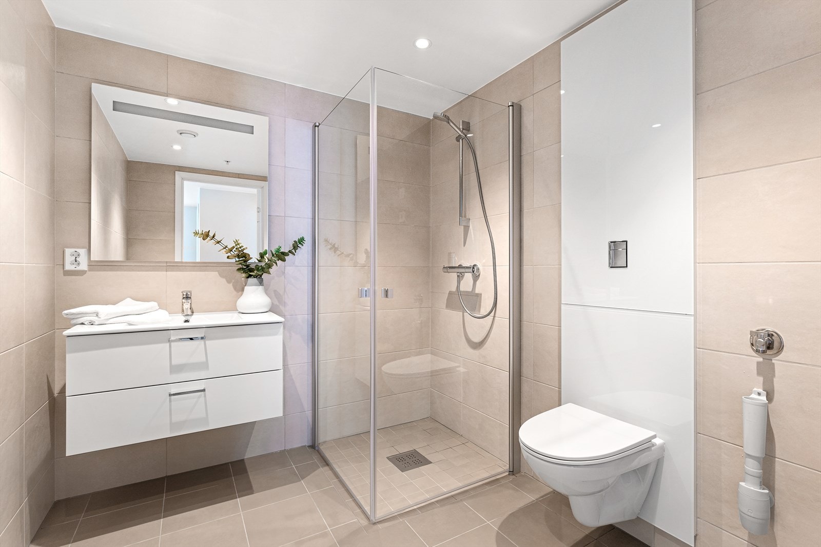 Lekkert bad med baderomsinnredning i hvitt porselen og skuffer med dempet lukking. Speil med integrert lys. Galleribilde