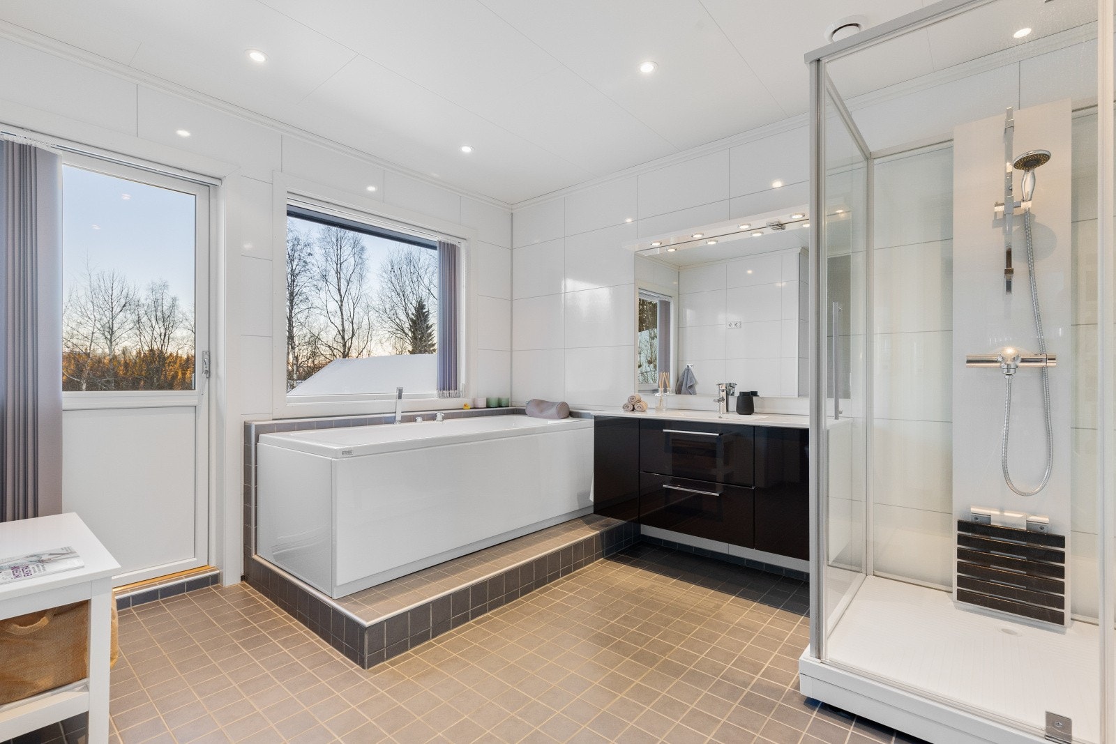 Stort baderom bestående av servant med underskuffer, dusjkabinett, badekar og vegghengt toalett Galleribilde