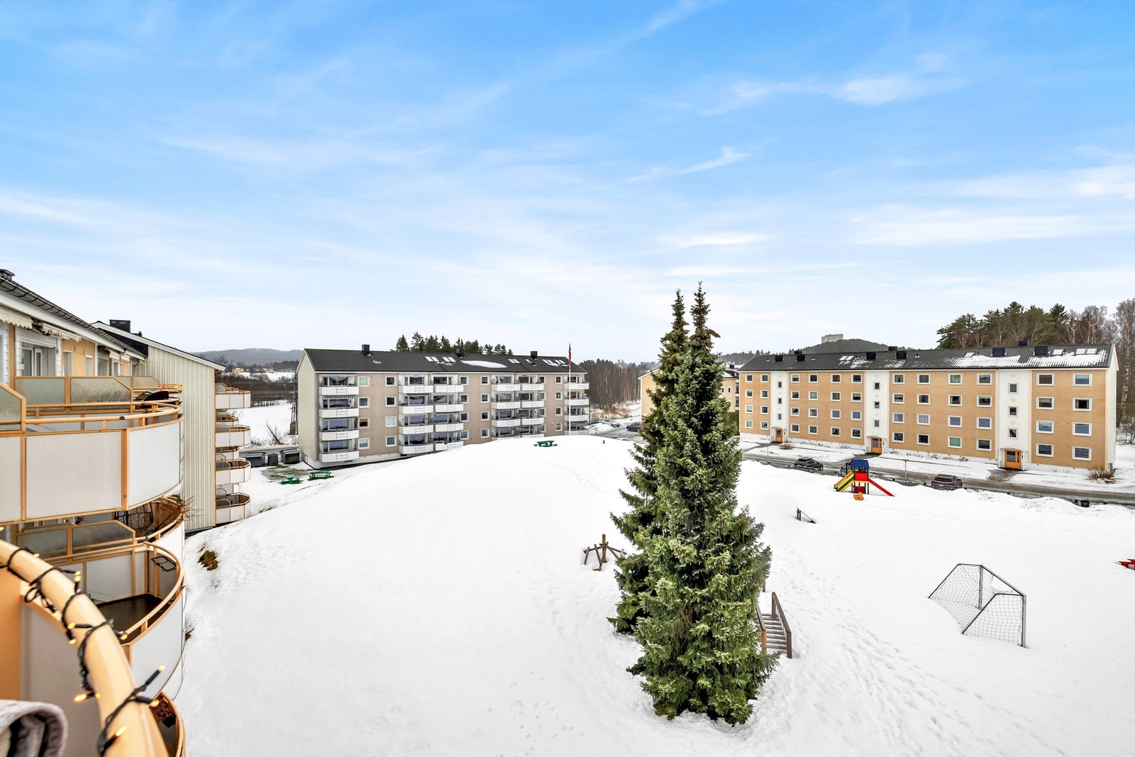 Utsikt fra balkongen til opparbeidet felles tomt med store grøntarealer, lekeplass, ballplass og sitteplasser. Galleribilde