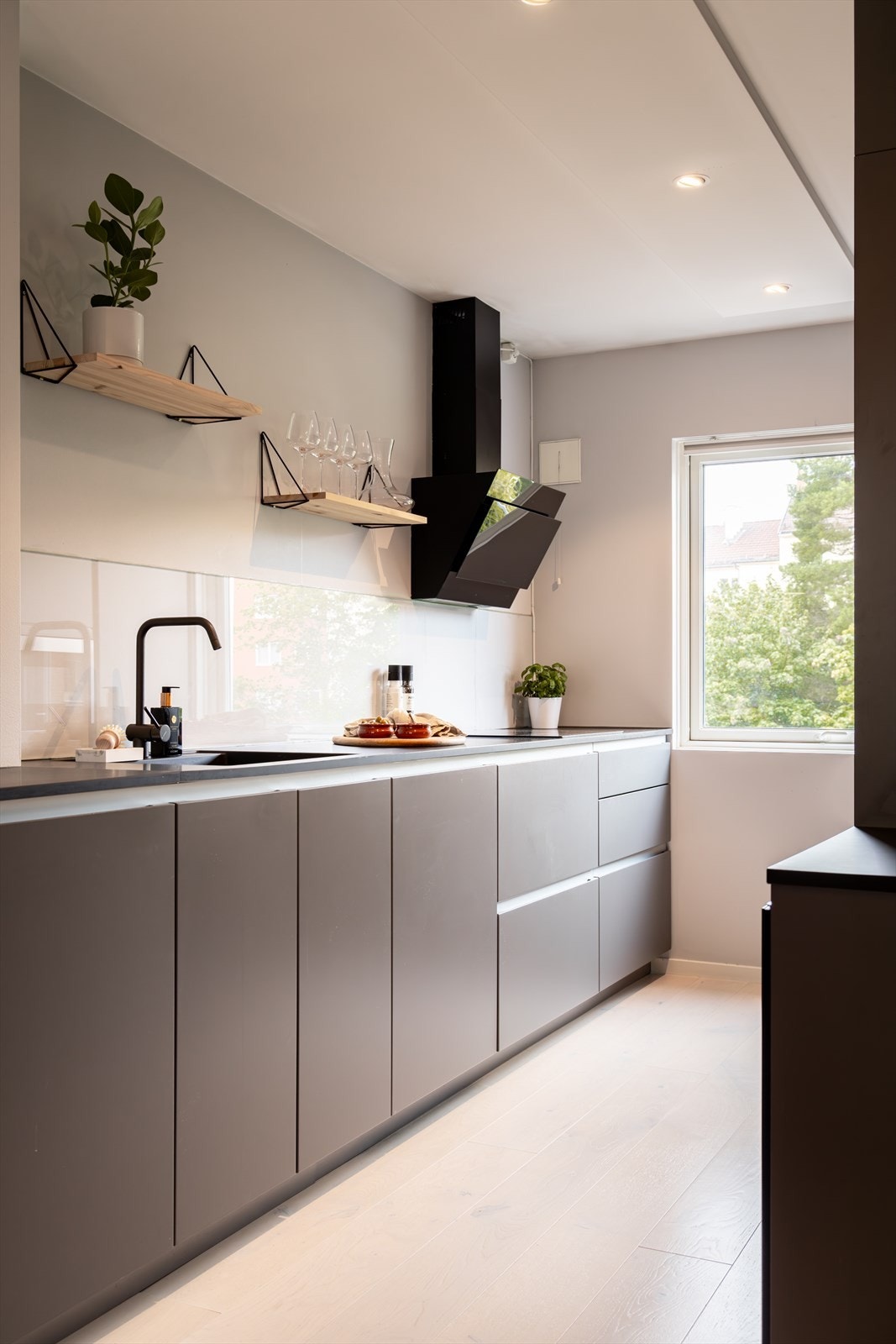 Et gjennomtenkt og linjelekkert kjøkken med mye skap og benkeplass. Galleribilde