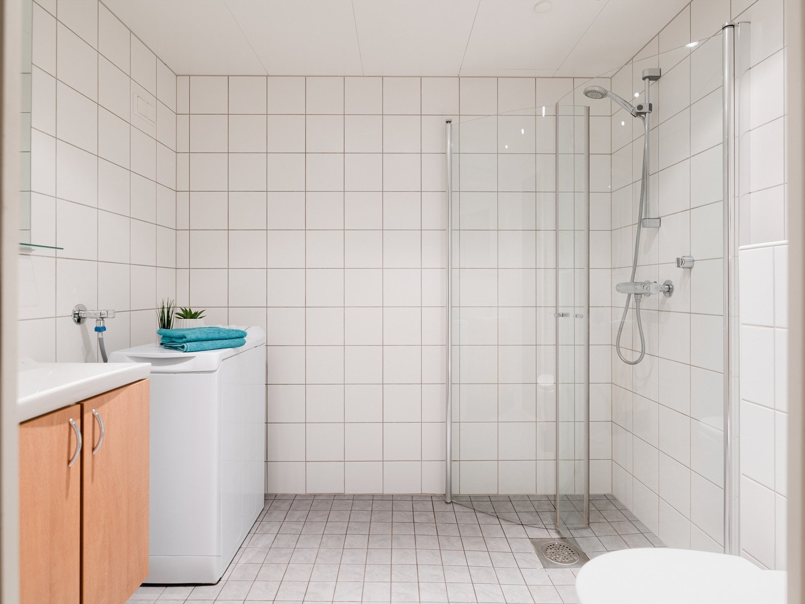 Lyst, flislagt bad i en lys og tidsnøytral utførelse. Varmekabler i baderomsgulv sørger for varme føtter året rundt. Galleribilde