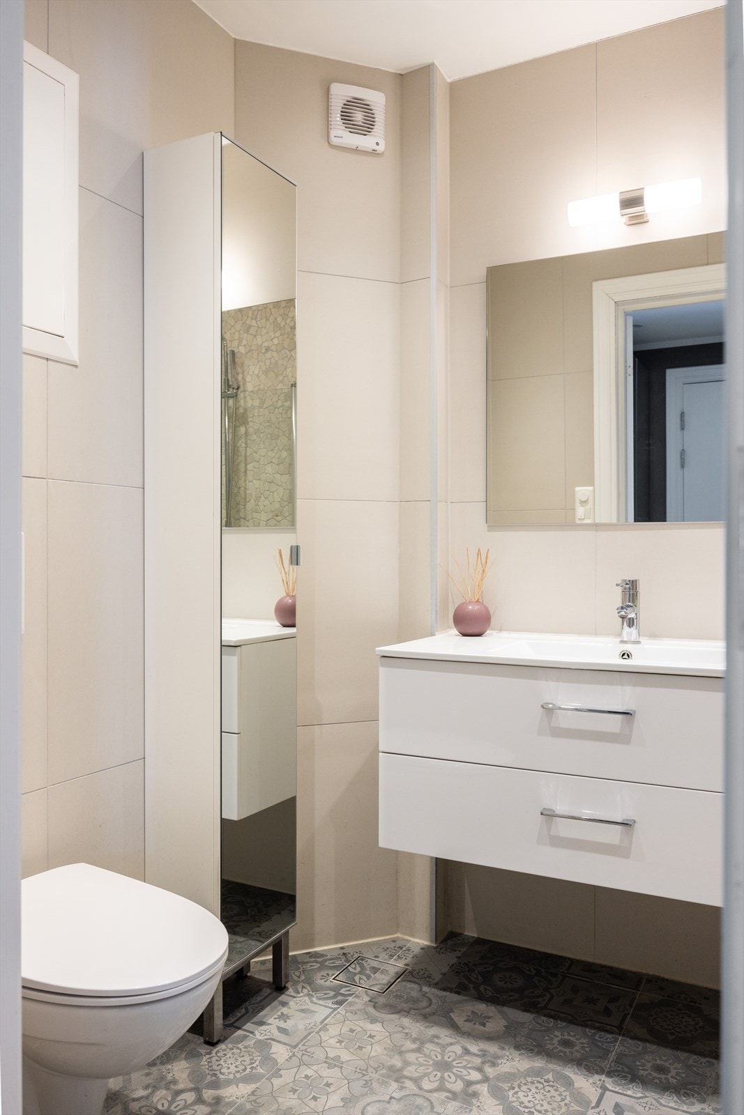 Badet er innredet med vegghengt klosett, servant nedfelt i innredning og dusjhjørne med svingbare glassdører. Galleribilde