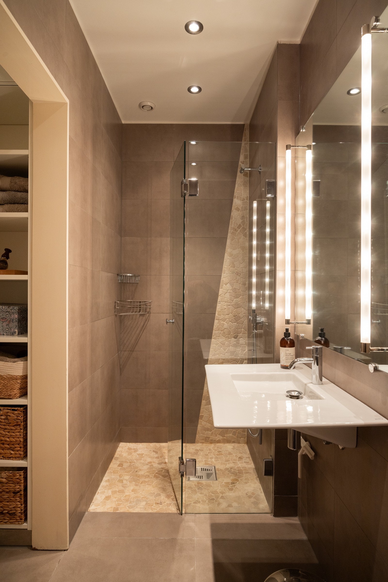 Flislagt baderom som består av bl.a. dusjhjørne, servant, vegghengt toalett og speil med lys. Galleribilde