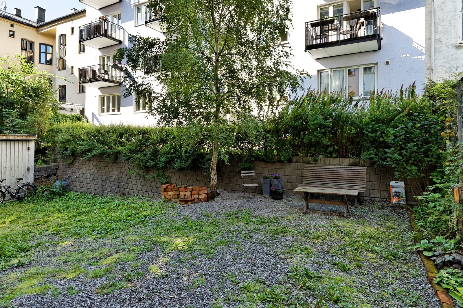 Opparbeidet bakgård med plenarealer, diverse beplantning, prydbusker og sykkelparkering Galleribilde