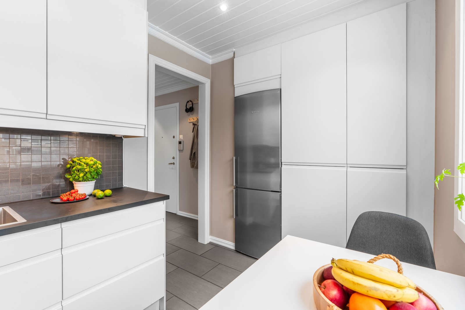 En vegg med innebygget høyskap gir godt med lagringsplass, og her er det plass til et frittstående kjøleskap. Galleribilde