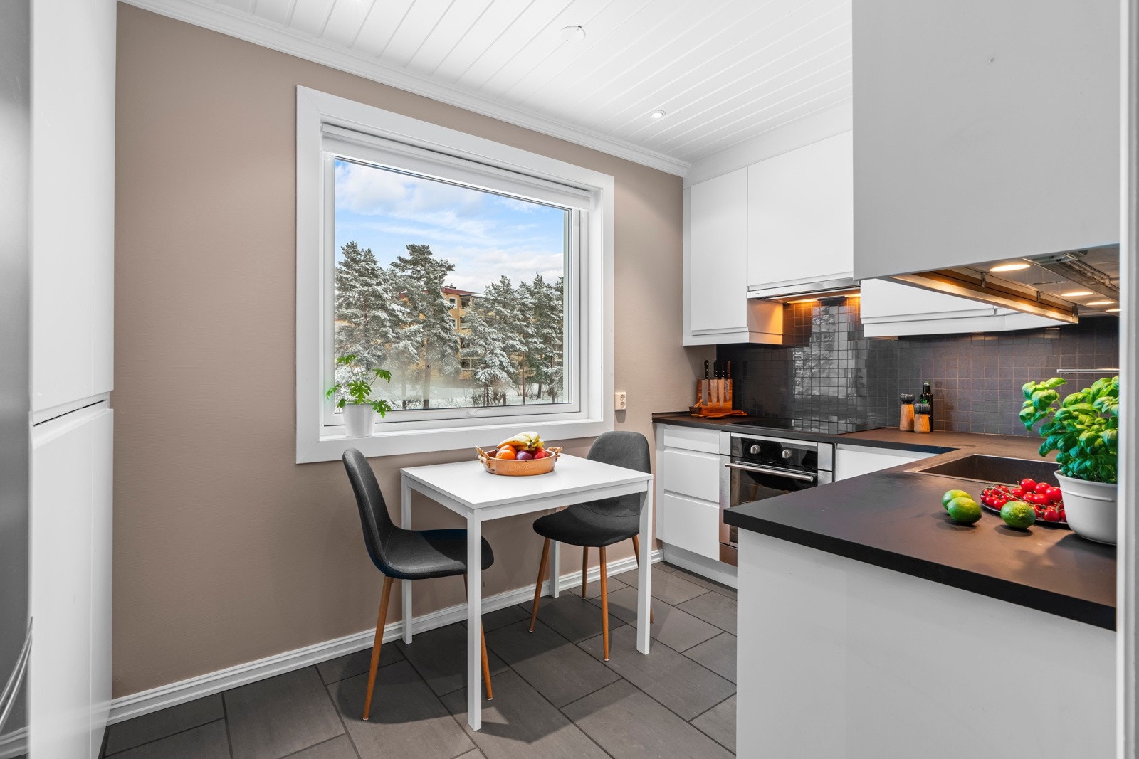 Kjøkkenet ligger i eget rom, og innredningen har et moderne uttrykk med slette fronter og dempefunksjoner, laminerte benkeplater og stålvask med 1-greps armatur. Galleribilde