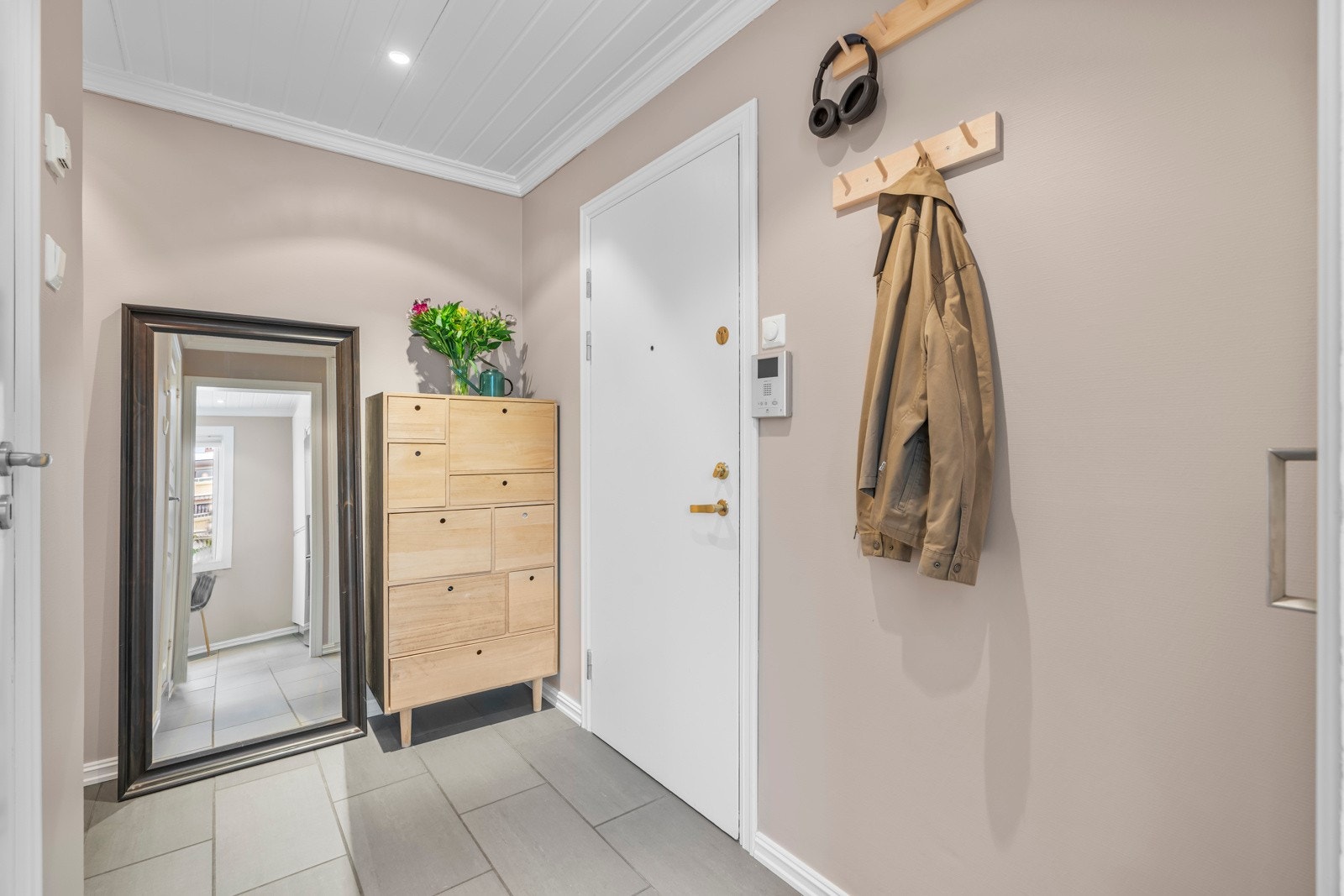 Entreen har et tidløst uttrykk med fliser på gulvet og slette vegger malt i en moderne tone. Galleribilde