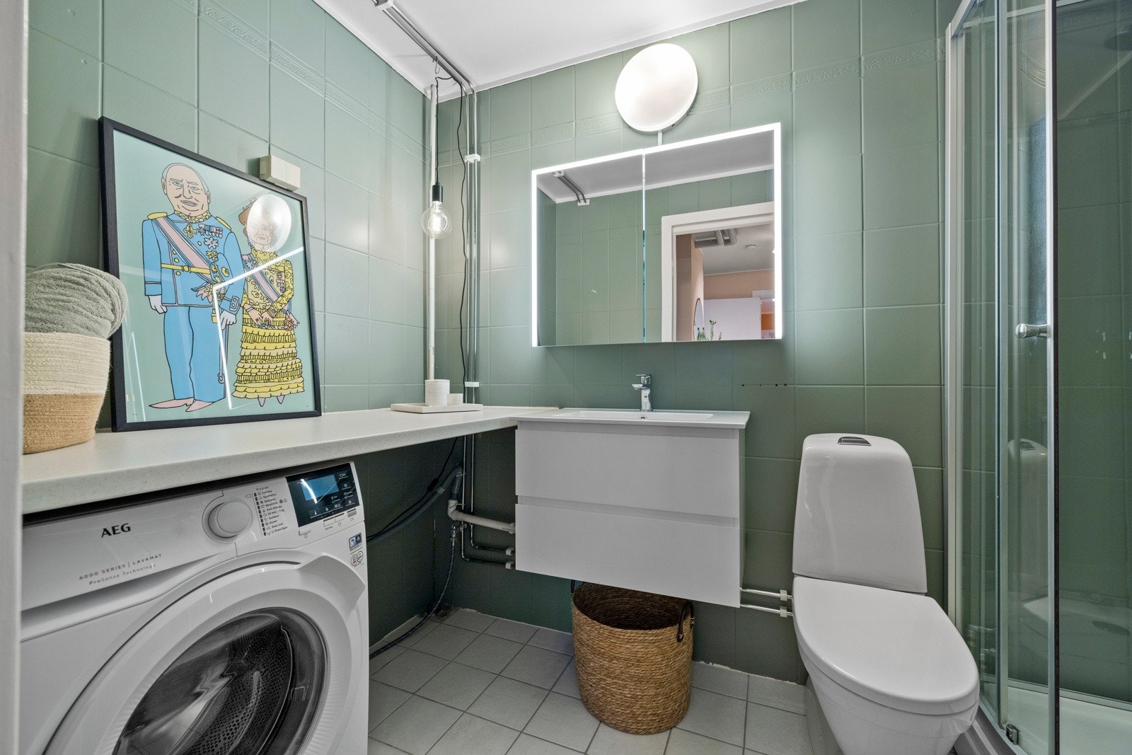 Badet er innredet med toalett, dusjkabinett og en hendig arbeidsbenk med opplegg for vaskemaskin under Galleribilde