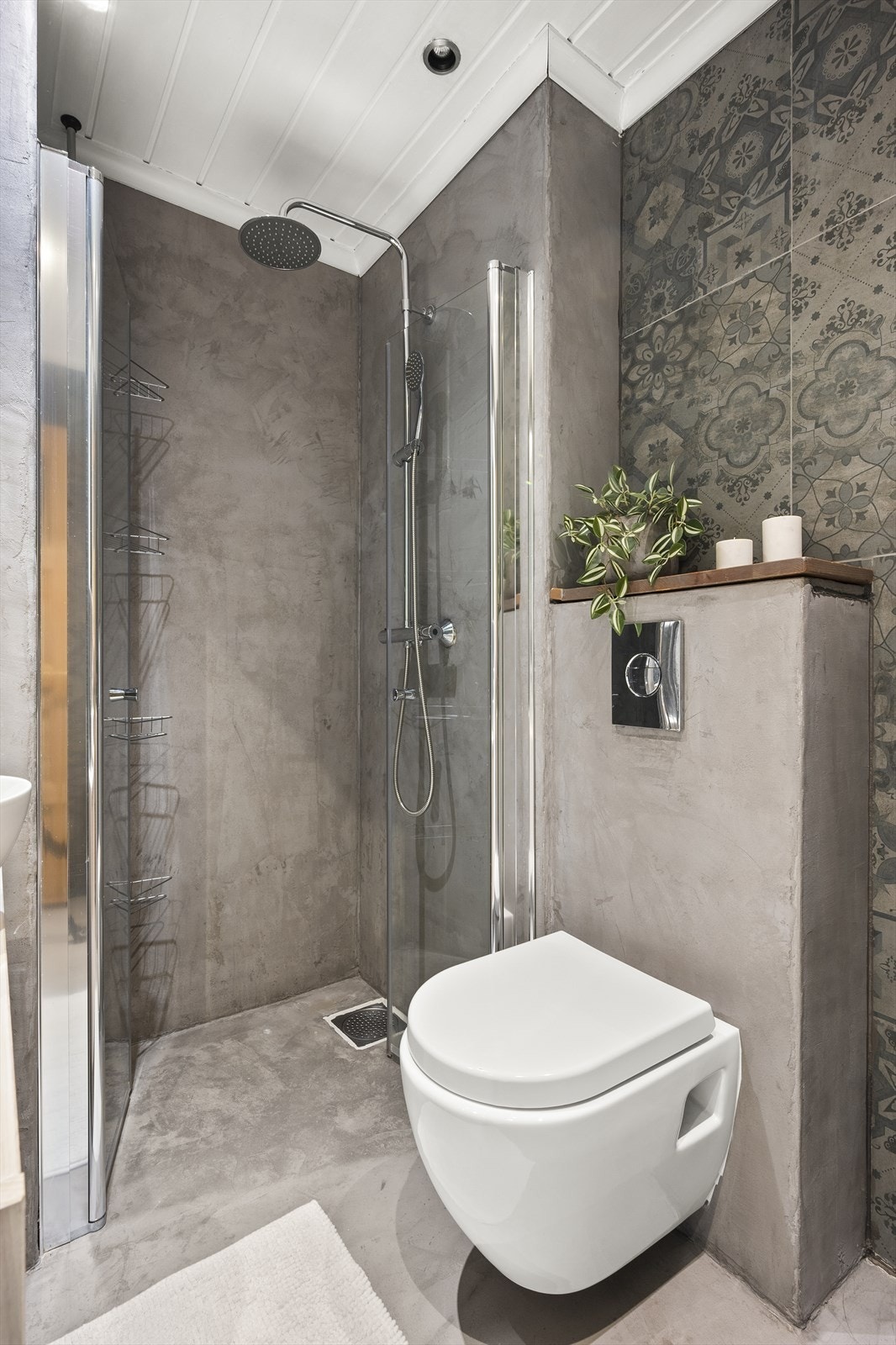 Badet er innredet med vegghengt klosett, dusjhjørne med svingbare glassdører og baderomsinnredning med servant på innredning, skap og speilskap. Galleribilde