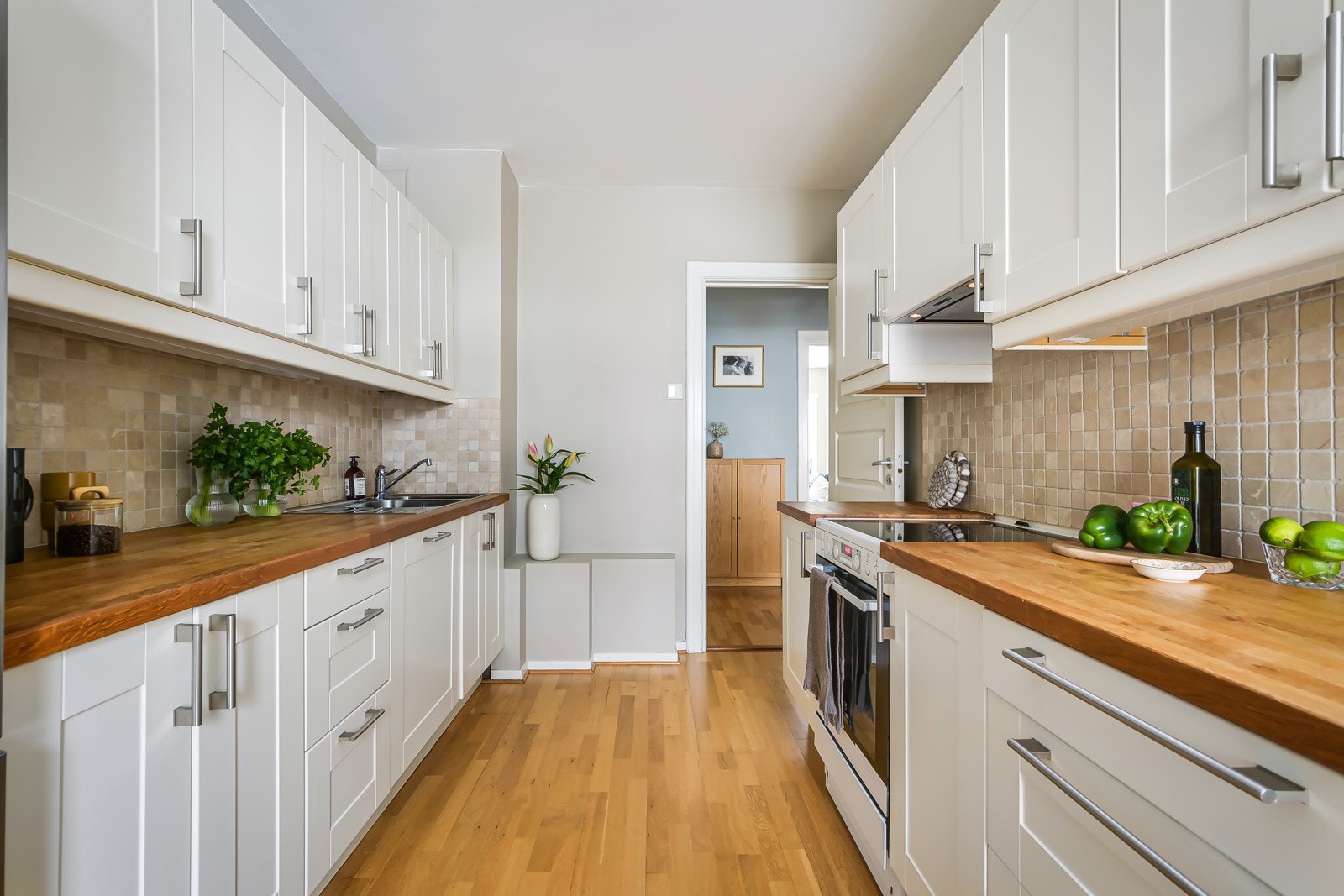 Pen og tidløs kjøkkeninnredning fra 2010 med lyse fronter og benkeplate av heltre med nedfelt oppvaskkum. Galleribilde