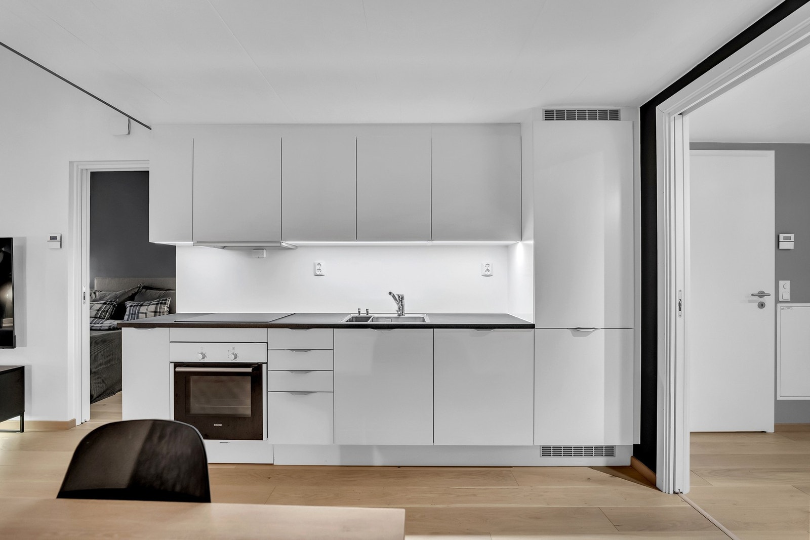 Kjøkkeninnredning med hvite glatte fronter og laminert benkeplate. Galleribilde