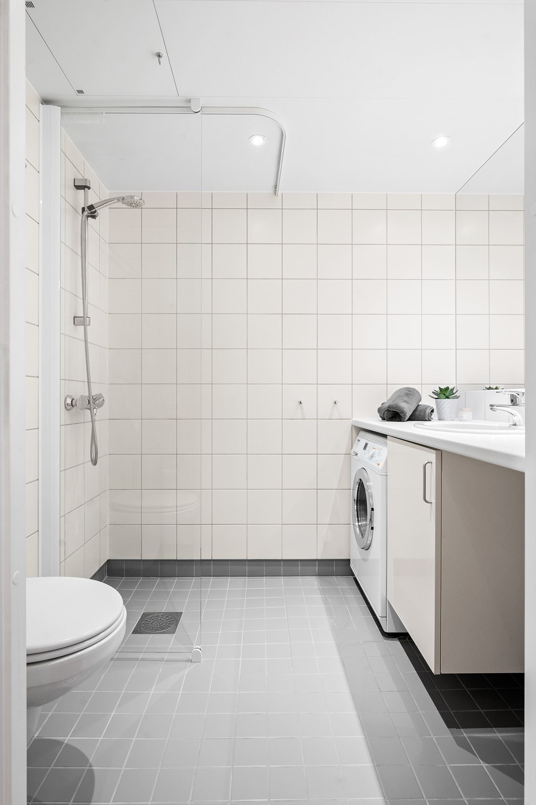 Innredningen består av servant med skapinnredning, innfelt speil over servant, vegghengt toalett og dusjhjørne med glassvegg. Galleribilde