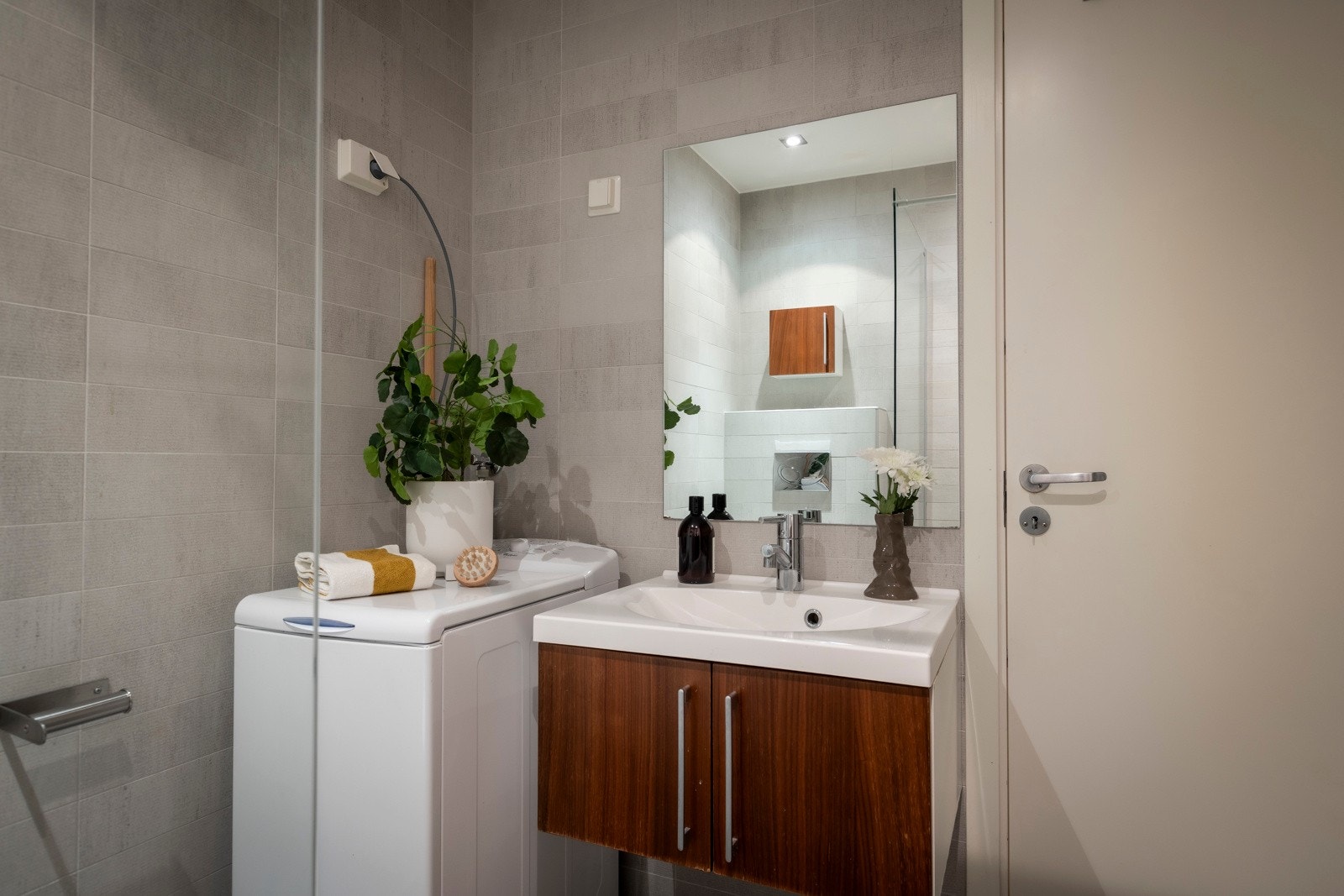 Badet er innredet med speil, servant med innredning, dusjhjørne med glassvegg og vegghengt toalett. Opplegg for vaskemaskin. Galleribilde