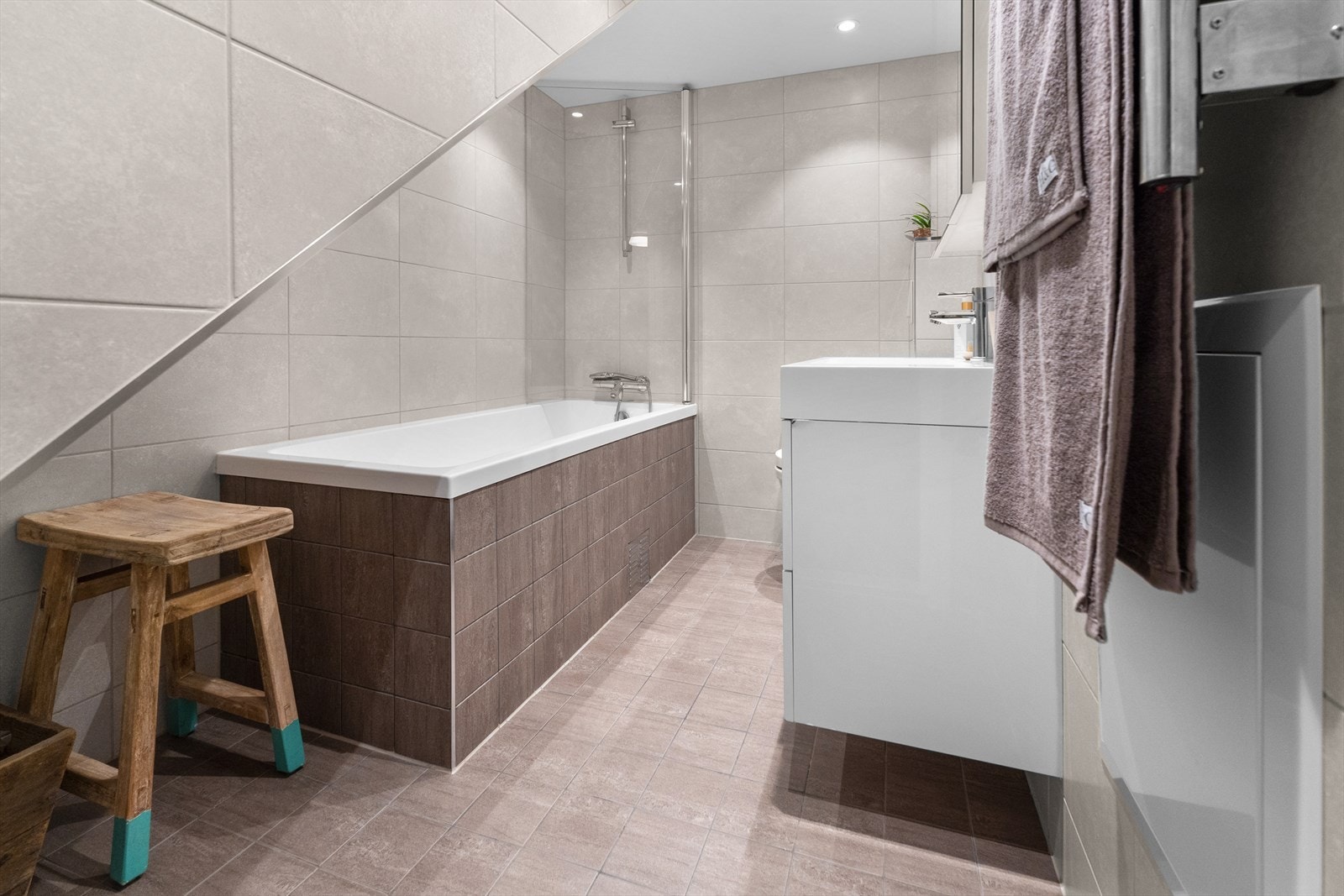 Pent og tidløst baderom. Rommet har innredning med nedfelt servant, veggmontert toalett og badekar. Galleribilde