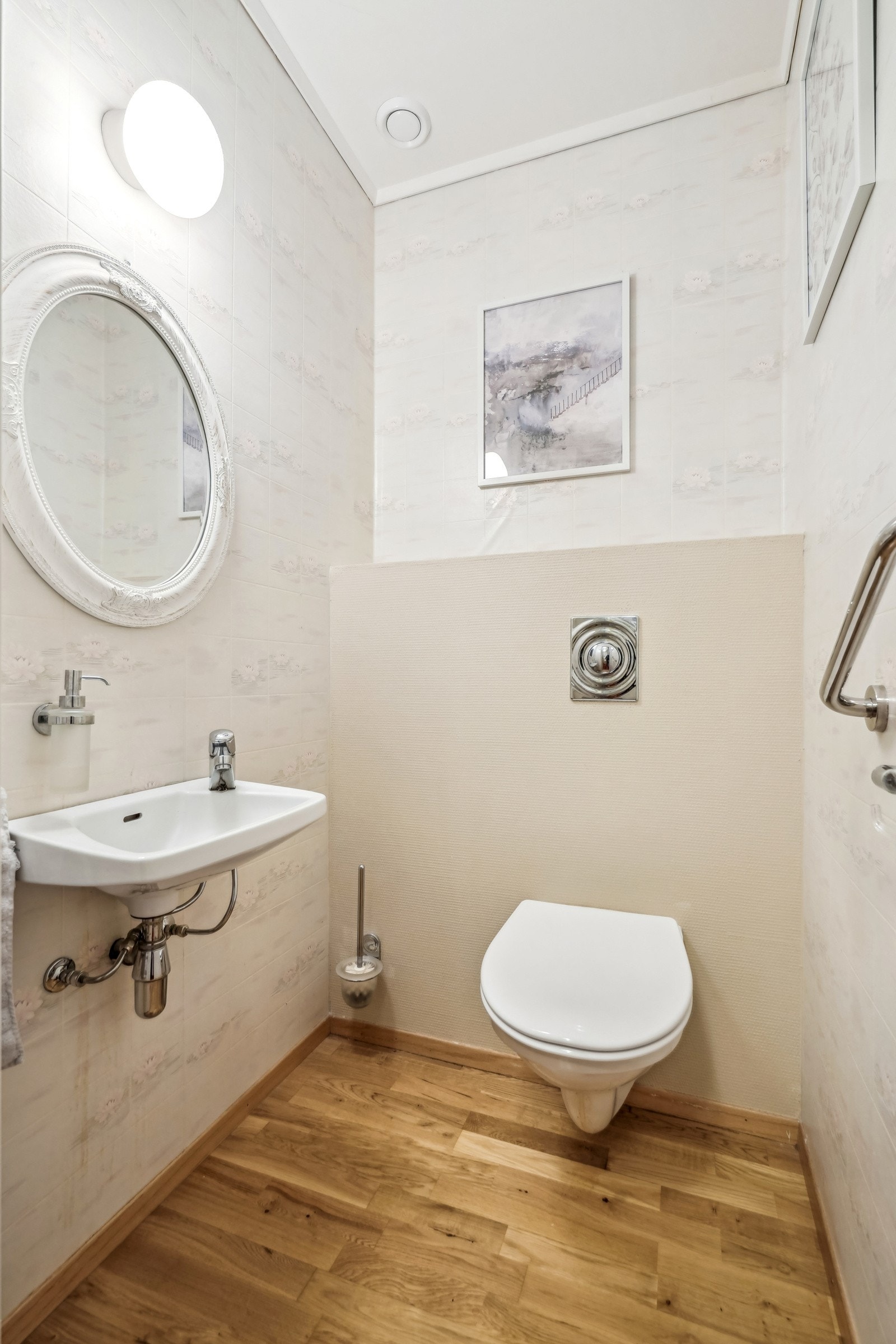 Toalettrommet har vegghengt toalett, servant og speil med lampe over. Galleribilde