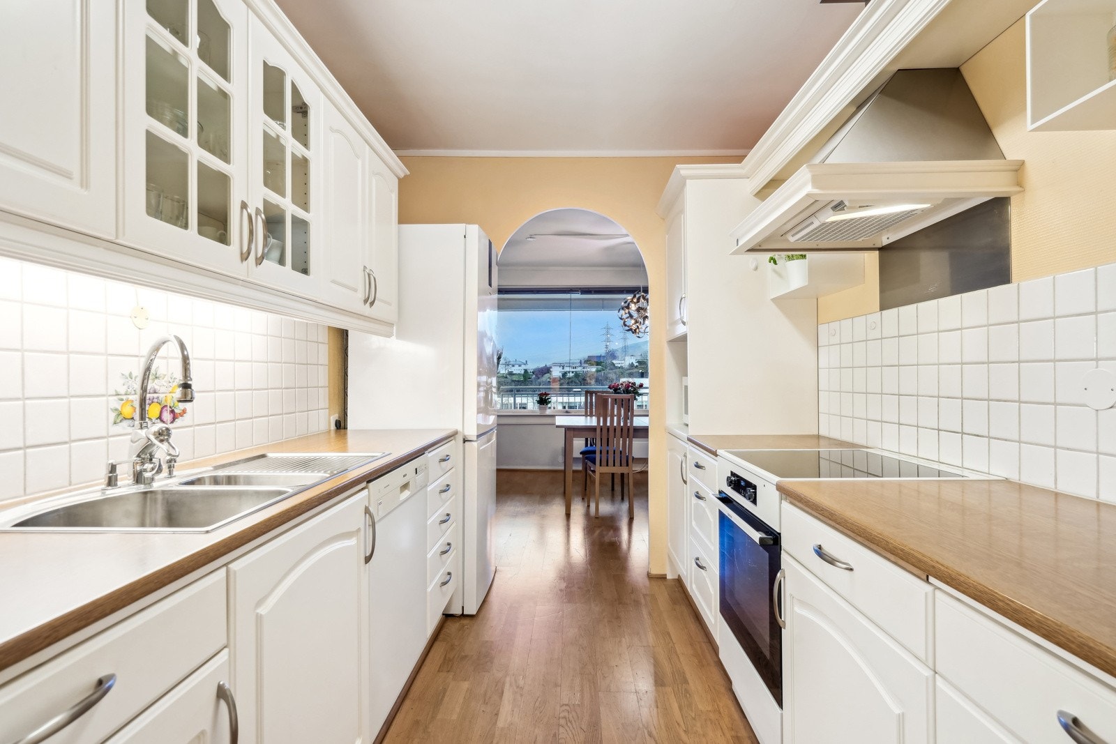 Kjøkkenet har lyse skapfronter, flislagt vegg over de laminate benkeplatene og integrerte hvitevarer. Galleribilde