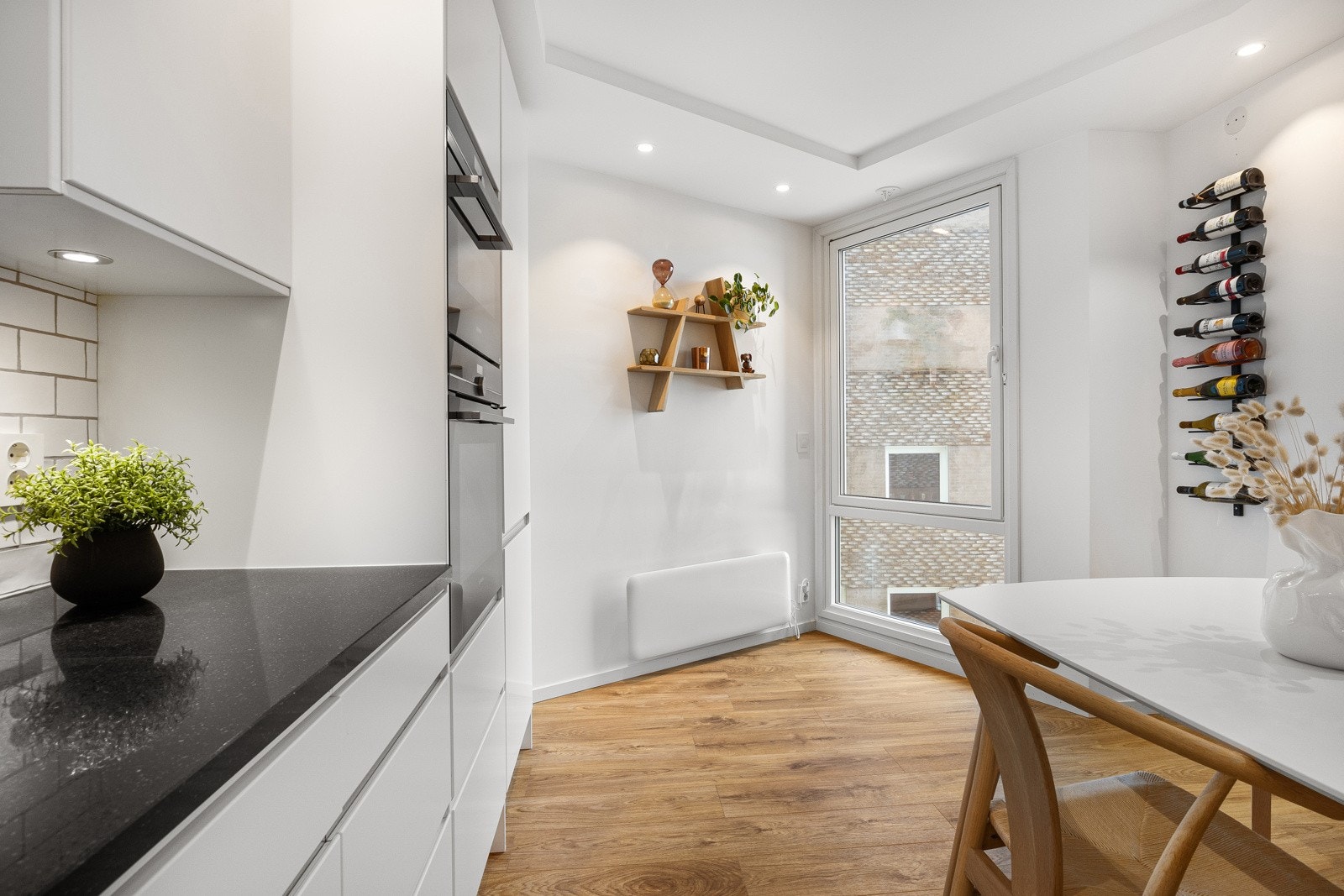 Det er sort Silestone benkeplate med vaskekum og hvite fliser i mursteinsmønster i bakkant. Galleribilde
