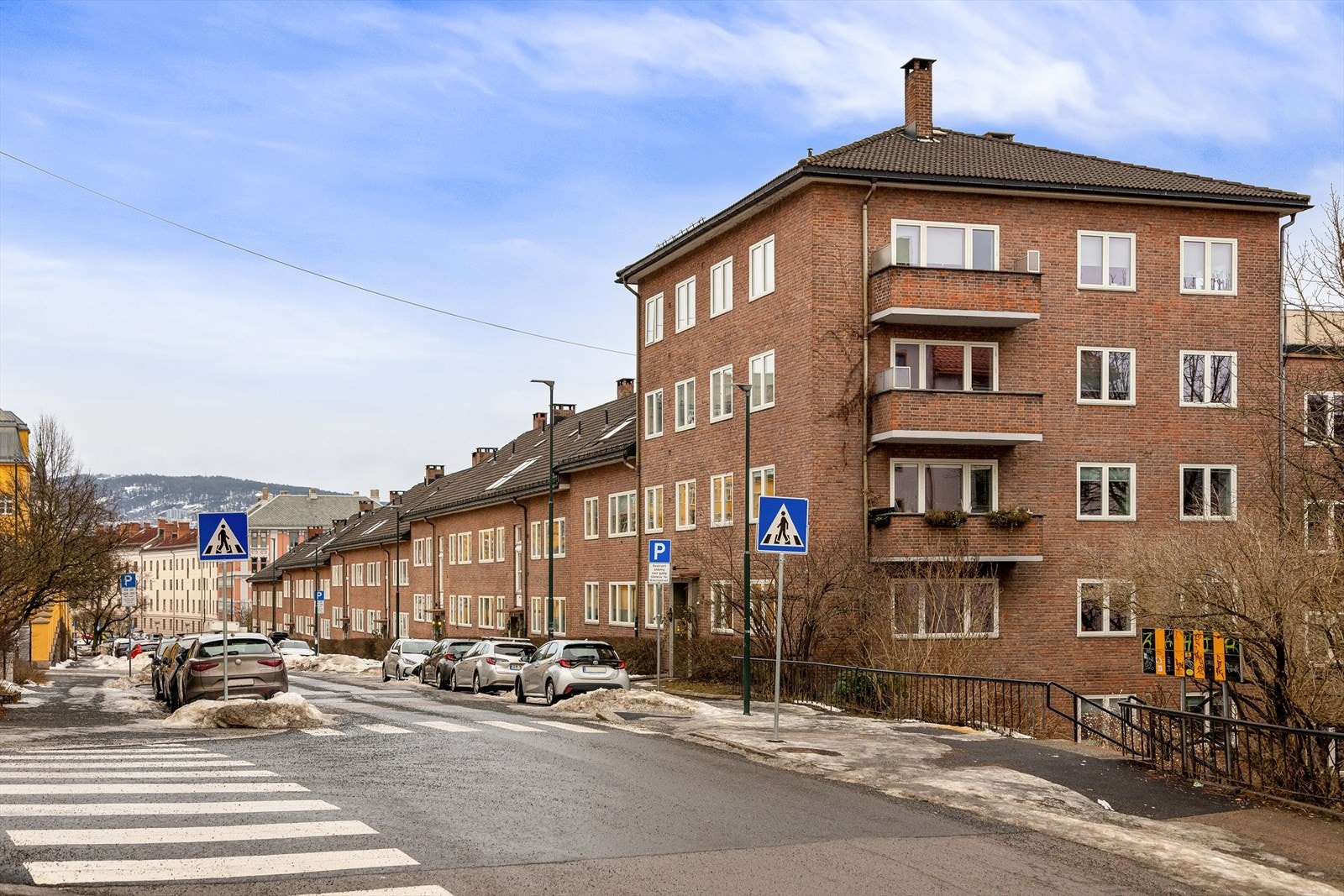Leiligheten ligger i en høy 1. etasje men oppleves praksis som i 2./3. etasje da blokken ligger i en skråning og det er to underetasjer i blokken. Kun to av vinduene i leiligheten er i 1. etasje. Galleribilde