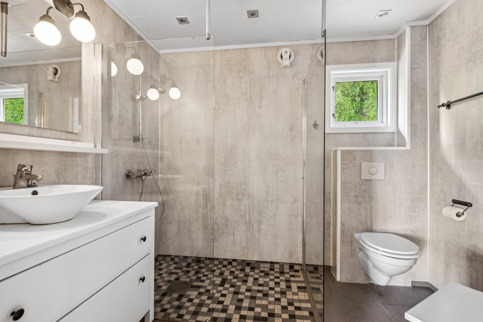 Innredningen er pent utført med romslige skuffer og hvit servant. Videre er det dusjhjørne og vegghengt toalett. Galleribilde