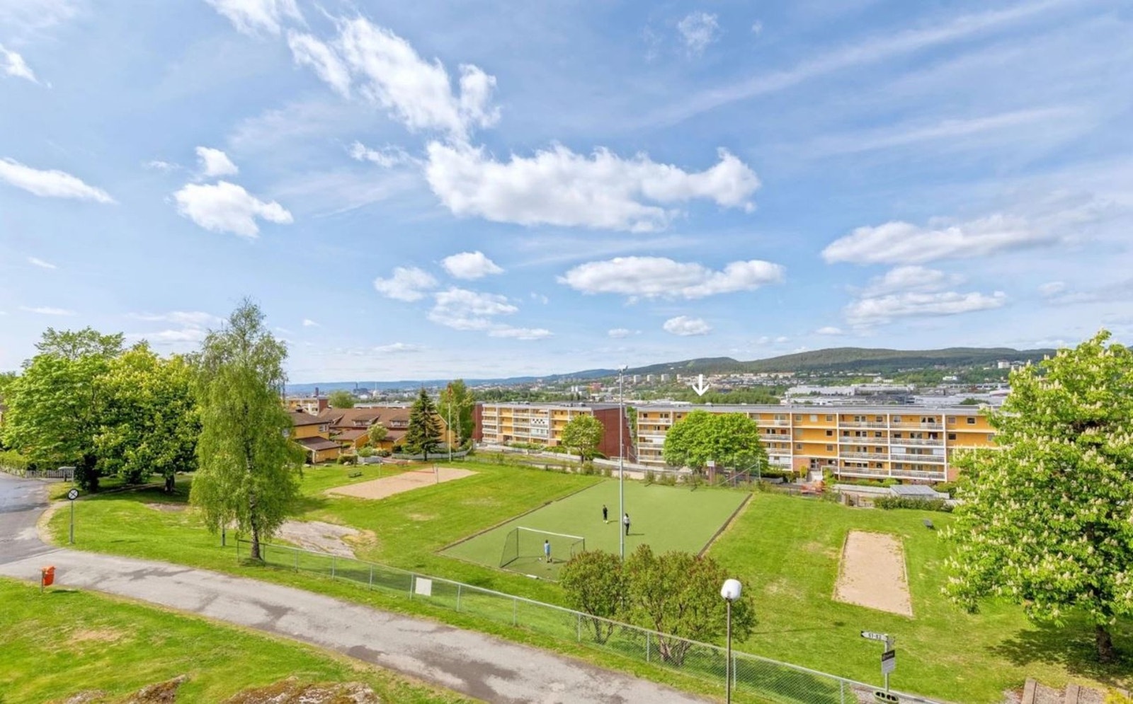 Borettslaget er omkranset av hyggelige grøntområder hvor du trygt kan slippe barna ut for å leke. Her finner du både lekeplasser og liten kunstgress-, sandvolleyball- og petanquebane. Boligen er markert med pil. Galleribilde