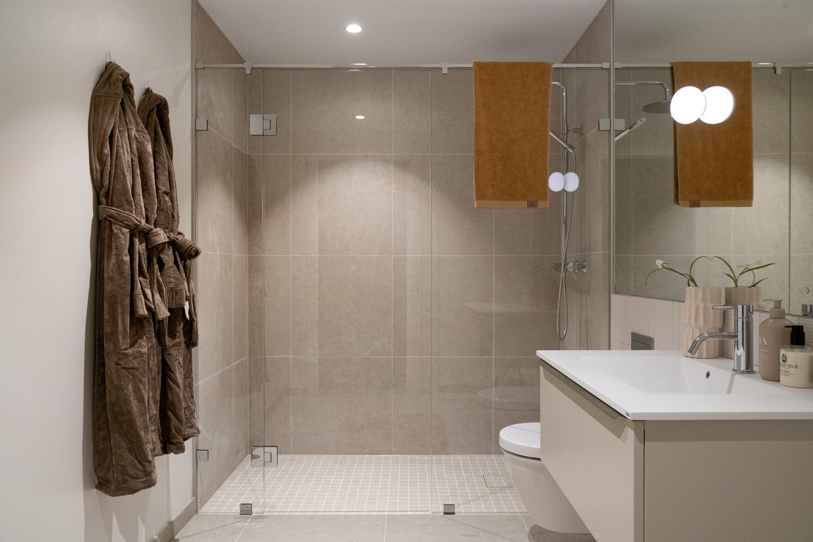 Baderom to; Interiørarkitektene har laget en helhetlig design med vegghengt servant med undermontert skuff fra HTH, store speilflater og vegghengt toalettet med innebygget sisterne. Galleribilde