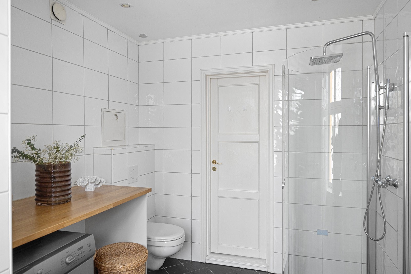 Flislagt gulv med varme, flislagte vegger og malt himling med downlights. Galleribilde