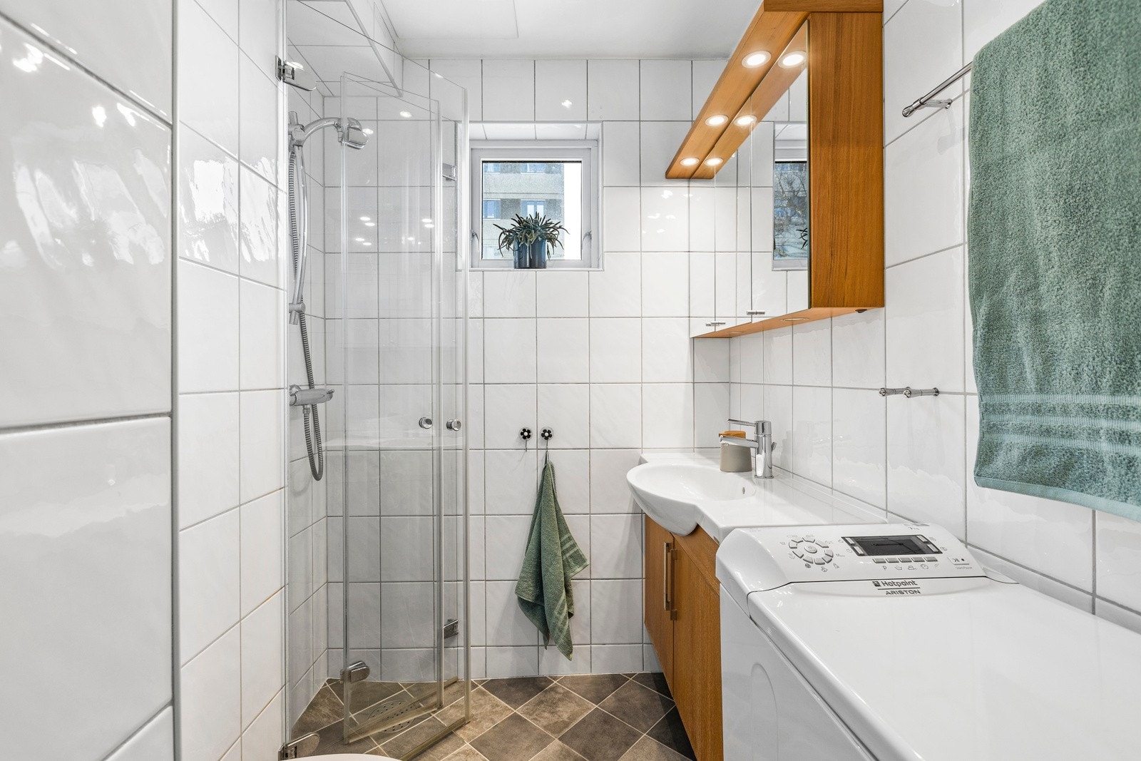 Badet inneholder vegghengt innredning med heldekkende servant, speilskap, vegghengt wc og dusjhjørne. Galleribilde