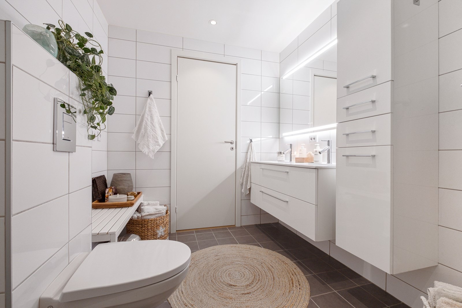 Badet er utstyrt med en romslig innredning med dobbel vask, vegghengt wc, varme i gulv og dusjvegger - inn døren rett frem ligger vaskerommet Galleribilde