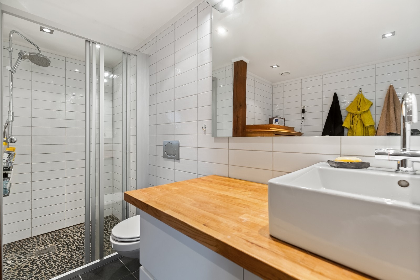 Stor dusjnisje med dusjdører og vegghengt toalett Galleribilde