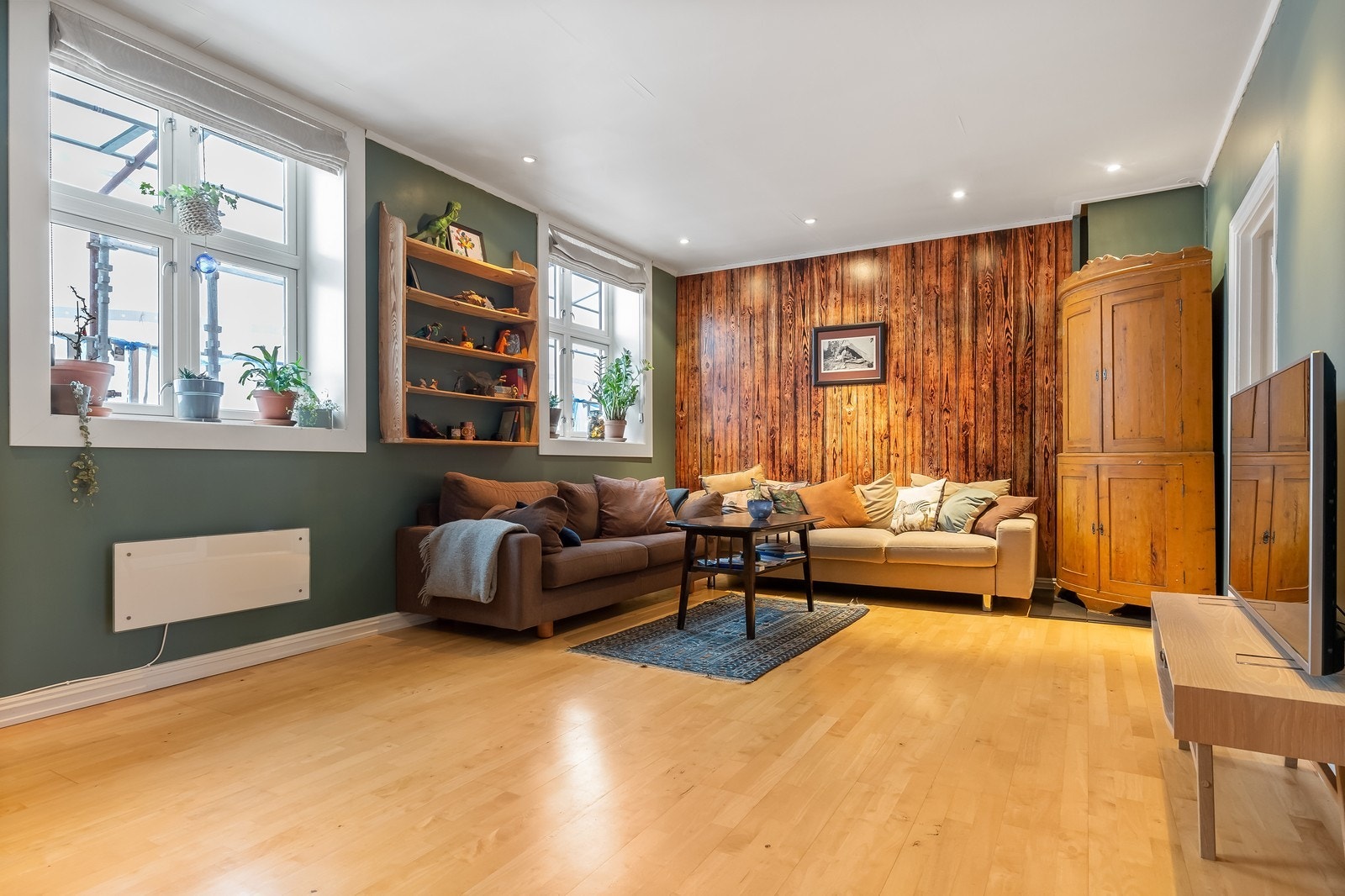 Romslig stue med stor sofagruppe og tv-møblement - Vedovn i stue som varmer godt Galleribilde