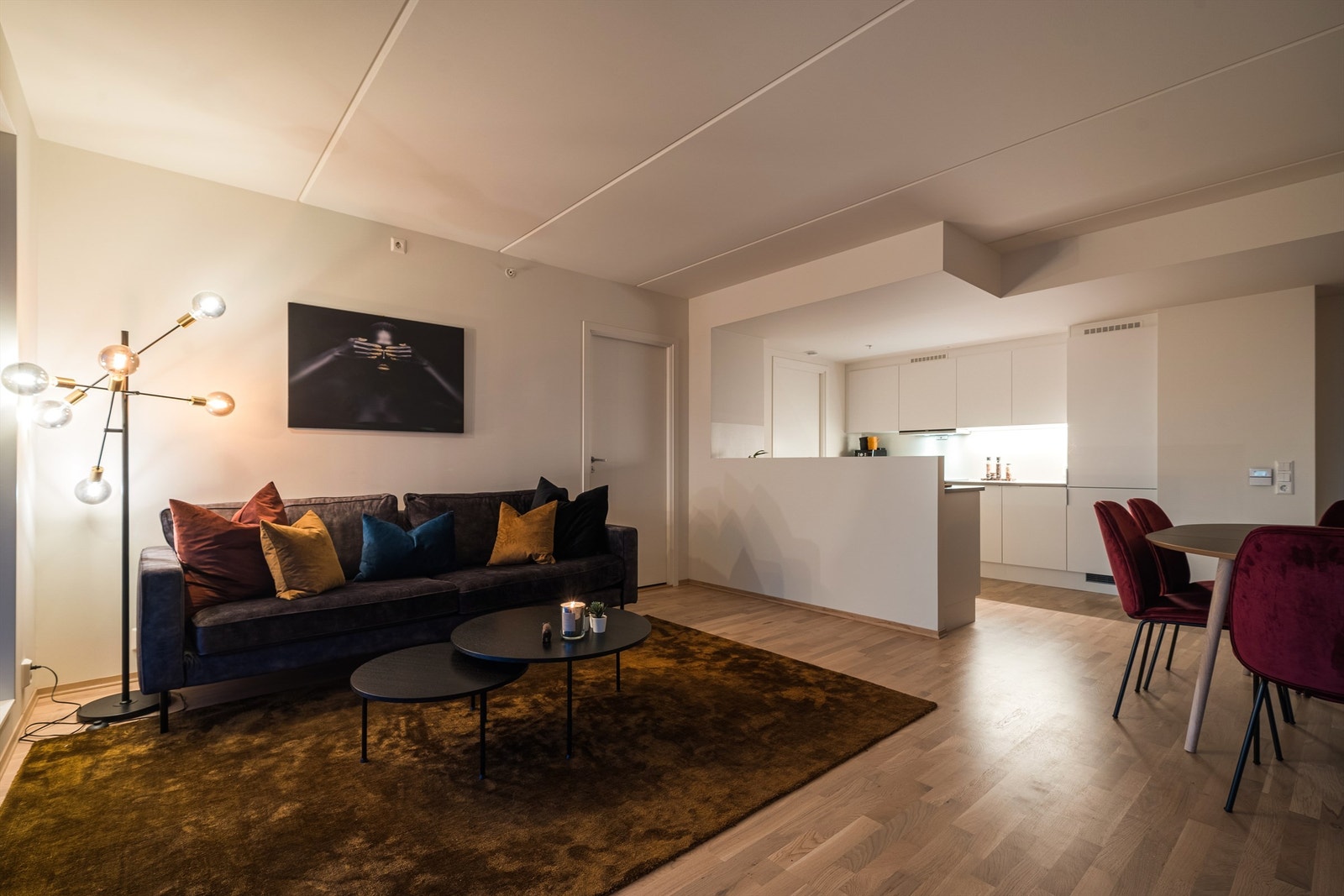 Tidløst, men moderne kjøkken i fin, åpen løsning med stuen. Kjøkkeninnredningen har hvite, glatte skapfronter og laminat benkeplater. Galleribilde