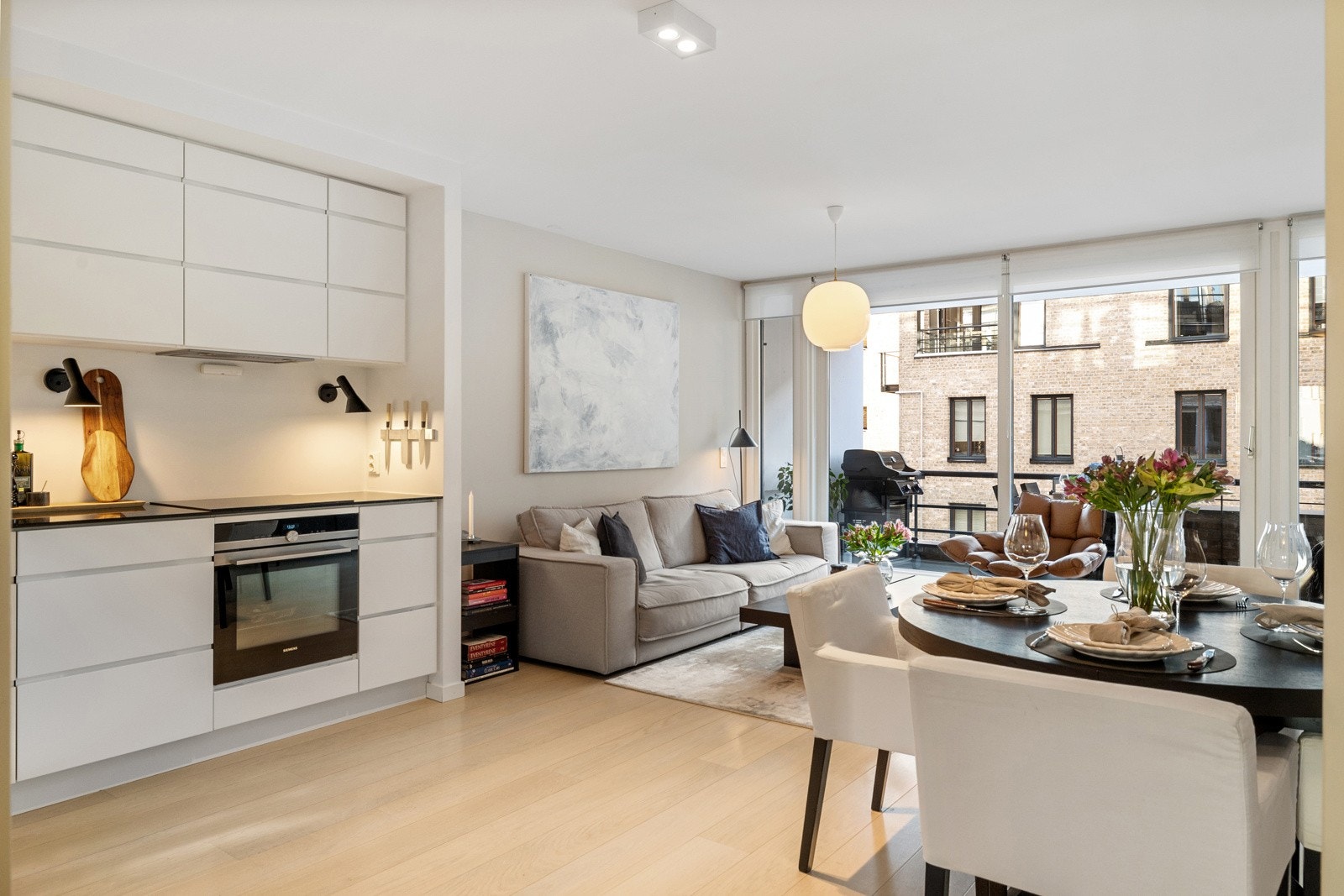 Leilighetens stue ligger i åpen løsning med kjøkkenet og er et innbydende allrom Galleribilde