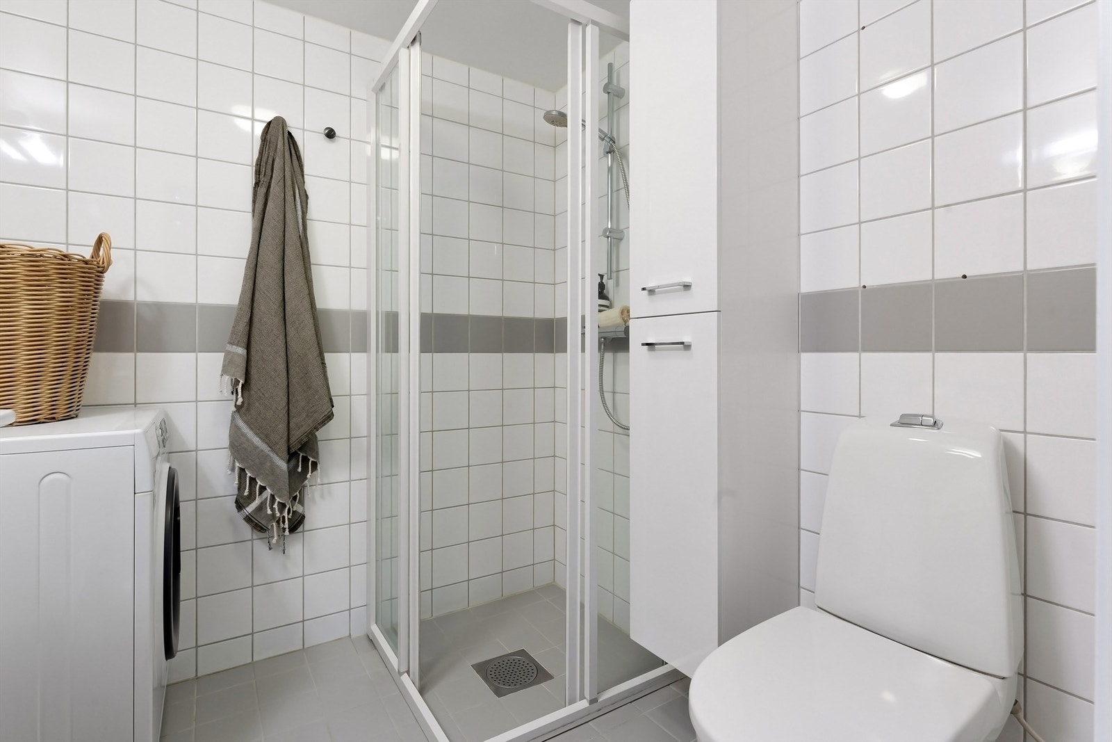 Innredningen består av gulvstående toalett, servant med innredning, innfelt speil over servant og dusjhjørne med skyvedører i herdet glass. Galleribilde