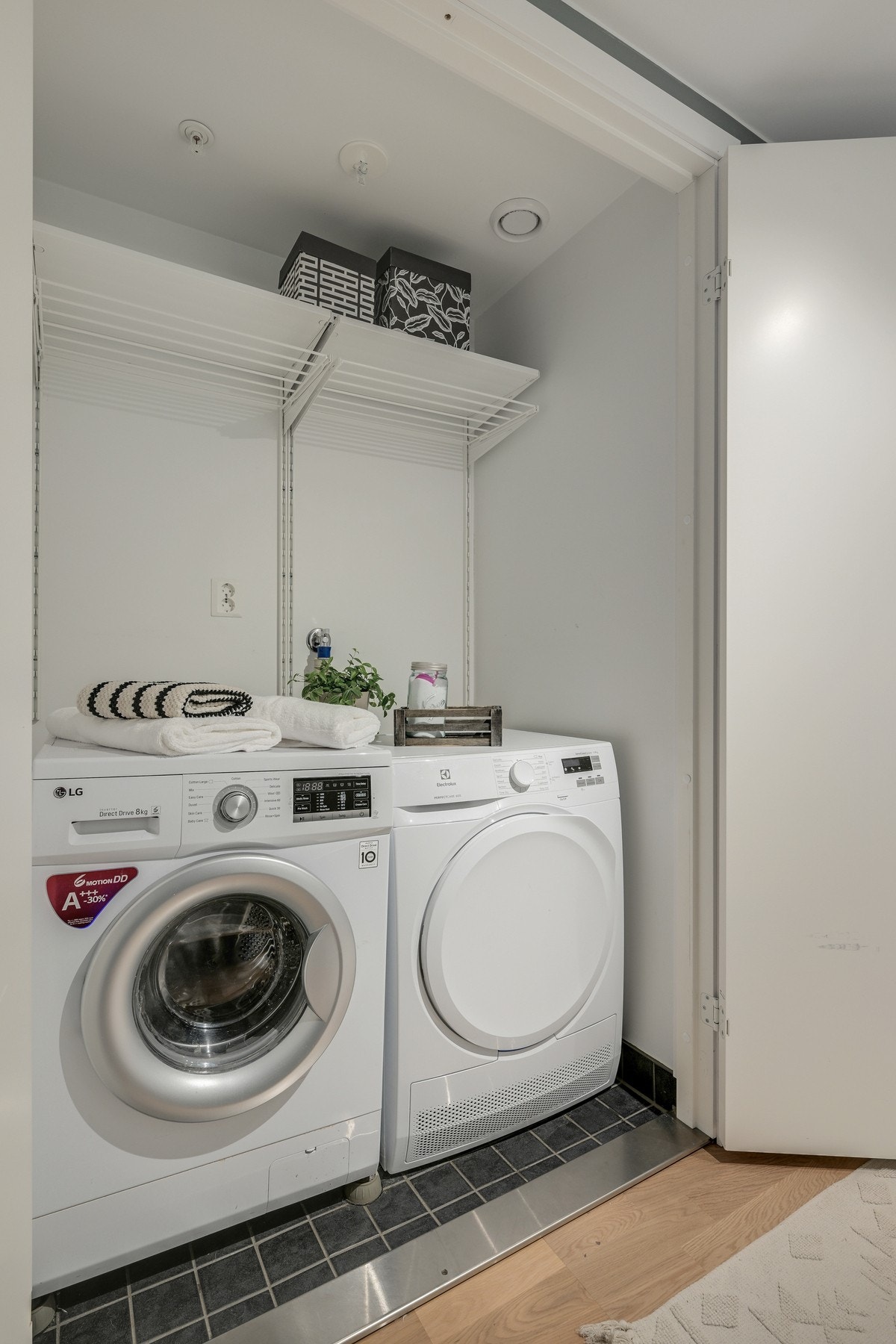 Vaskerom med flislagt gulv, opplegg for vaskemaskin, samt hyllesystem for oppbevaring. Galleribilde