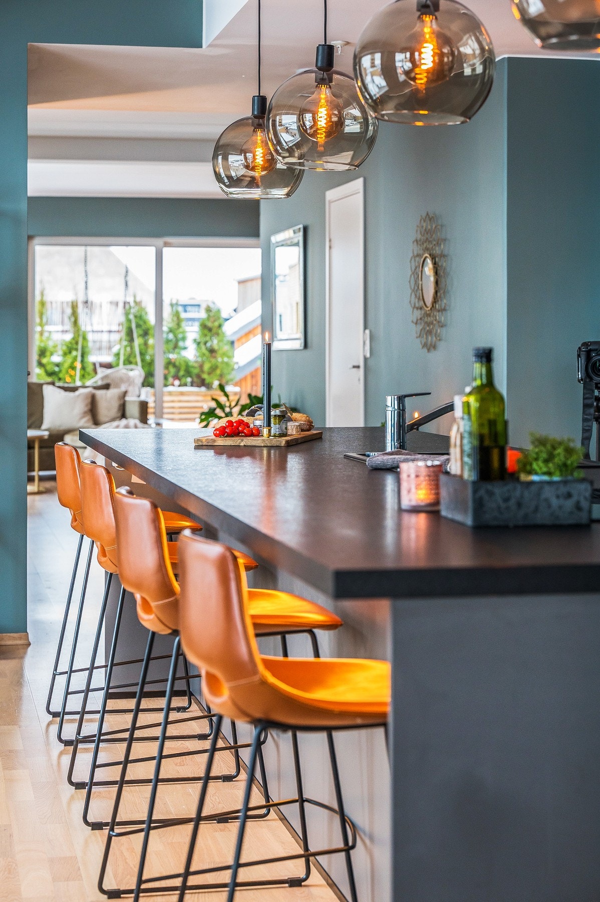 Kjøkkenet har en stor kjøkkenøy med mørk laminert benkeplate og moderne belysning. Galleribilde