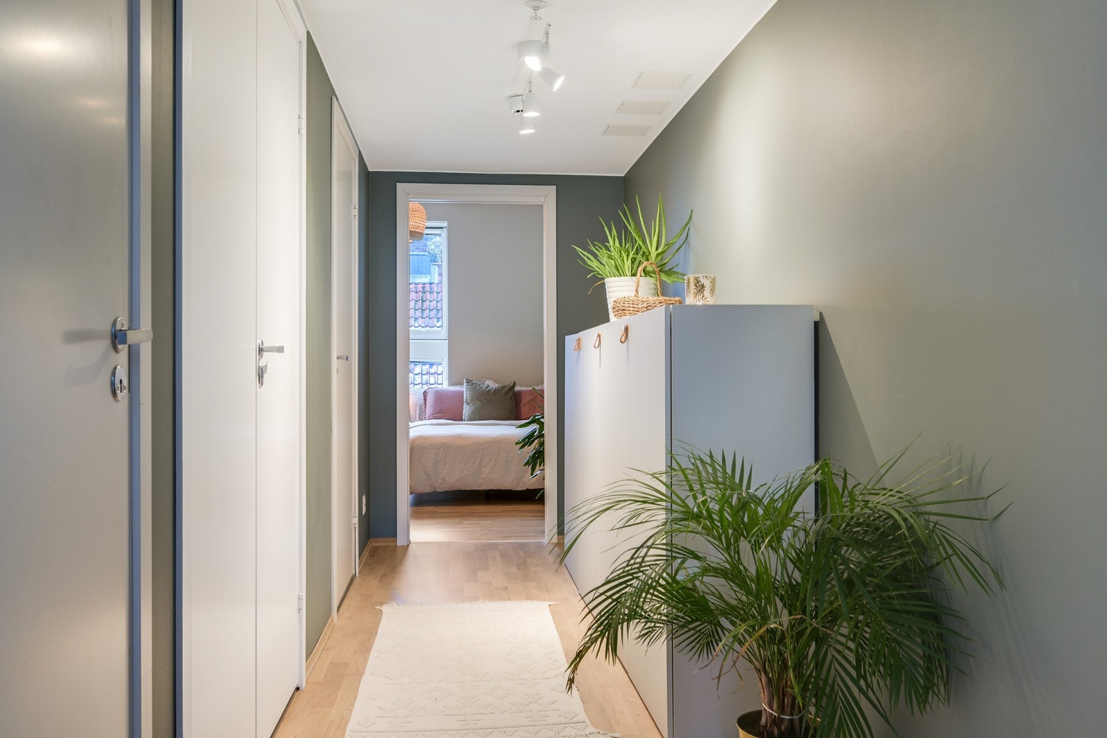 Lys gang med grønne vegger og parkett. Her har man nok av oppbevaringsplass. Galleribilde