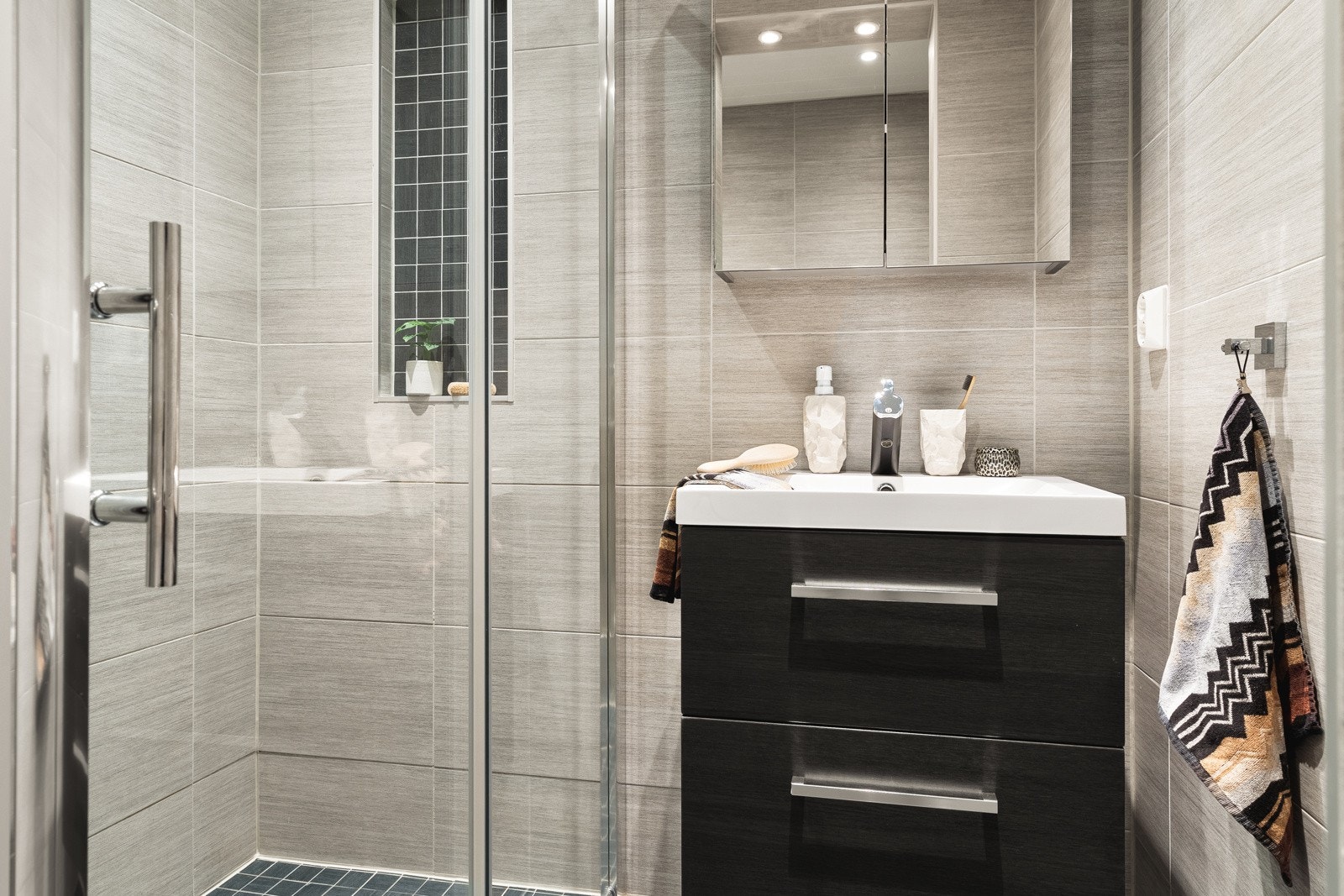 Moderne innredning som består av stor dusj med glassvegger, vegghengt toalett og en stilren baderomsinnredning. Galleribilde