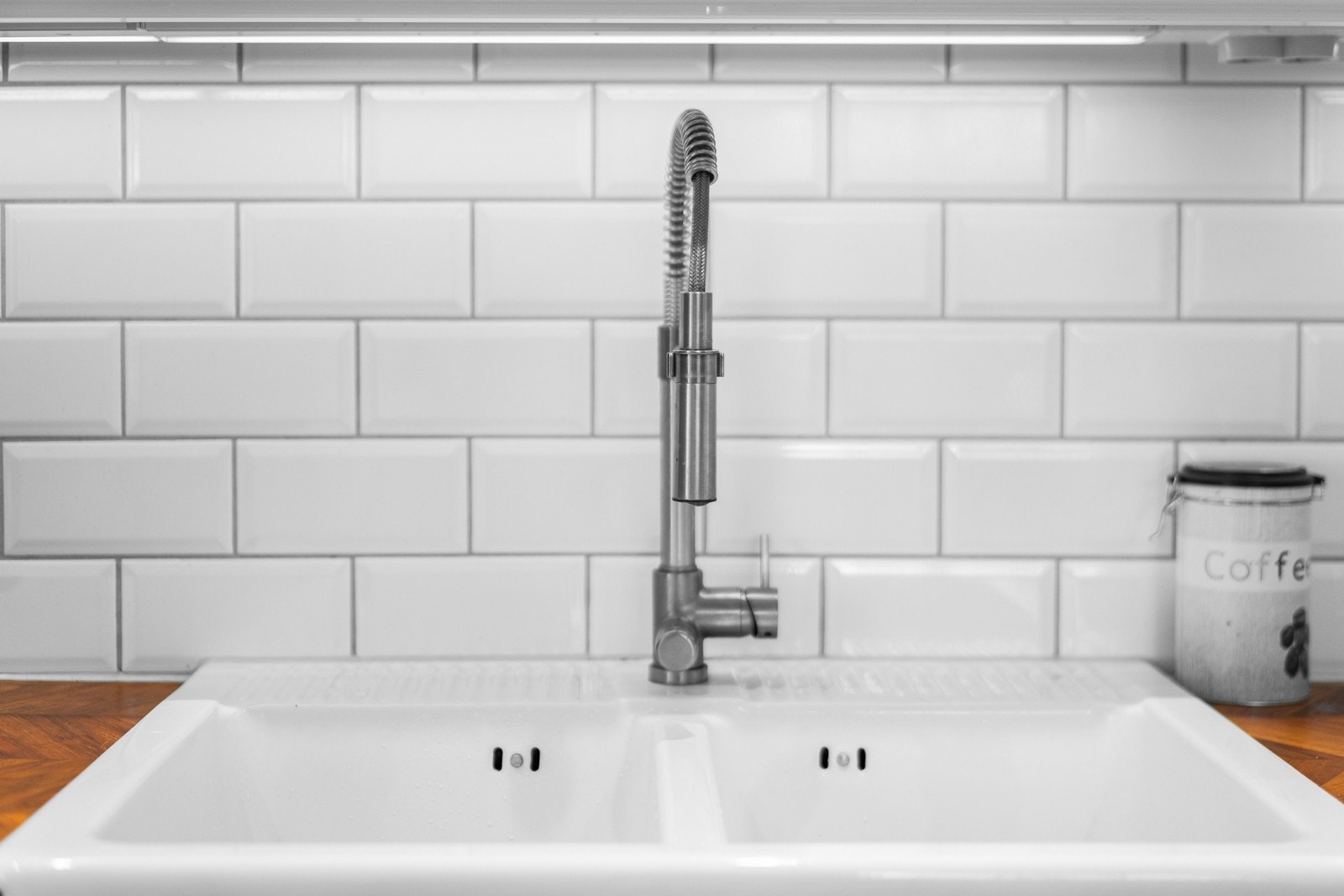 Det er nedsenket dobbel oppvaskkum i porselen med ettgreps armatur samt fliser mellom benkeplate og overskap Galleribilde