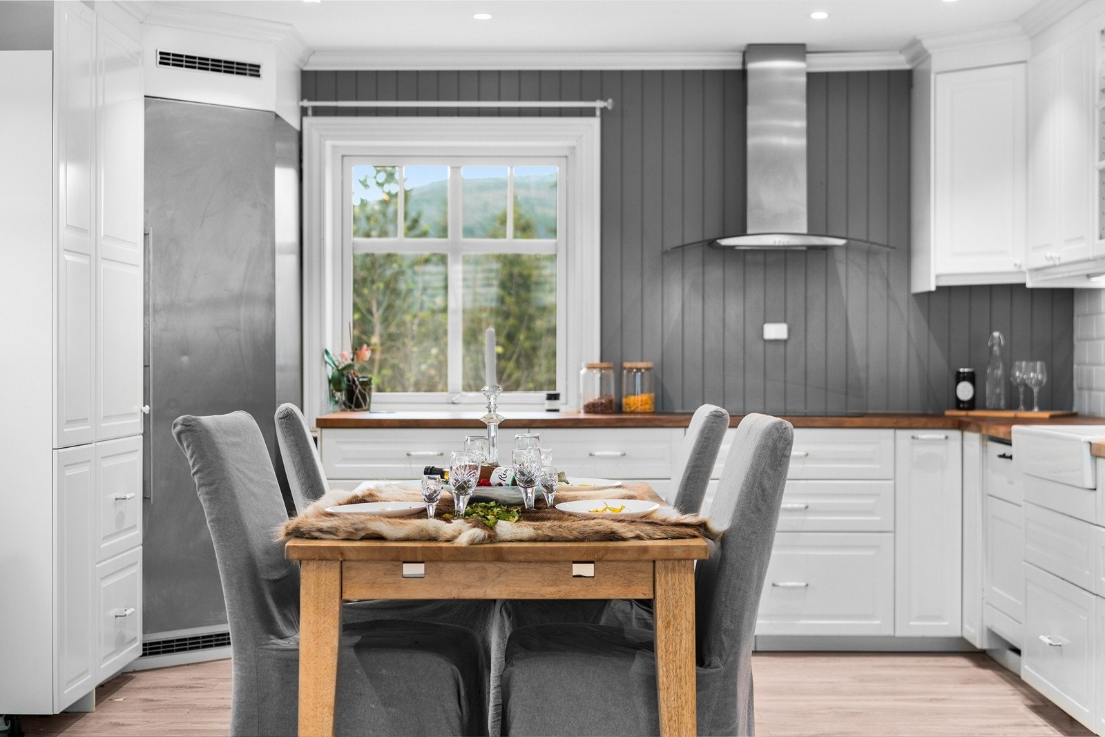 Kjøkkenet har innredning i profilerte fronter i matt hvit utførelse og benkeplate i treverk Galleribilde