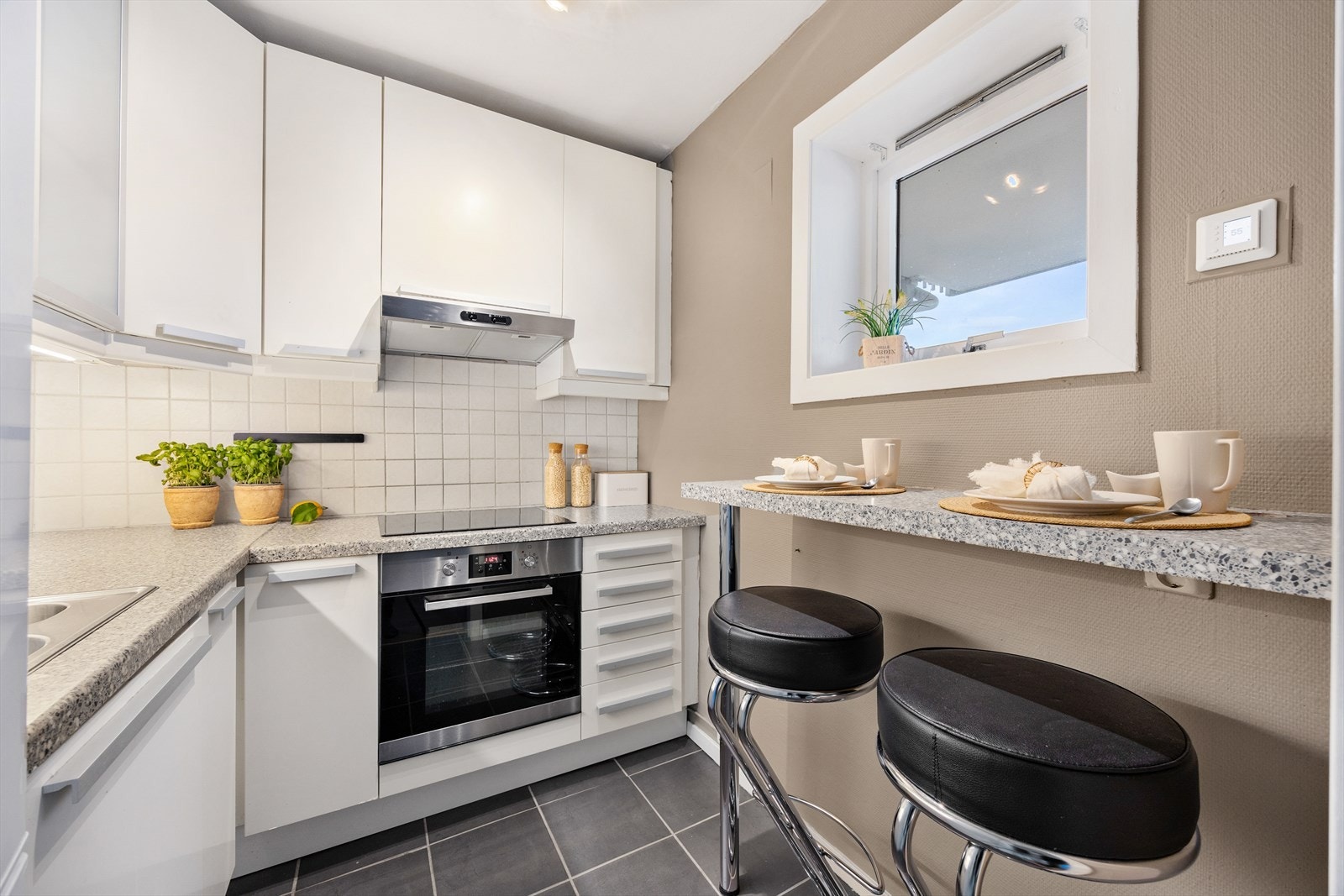 Kjøkkenet har innredning med hvite glatte skapfronter, laminat benkeplate og spiseplass ved vegg Galleribilde